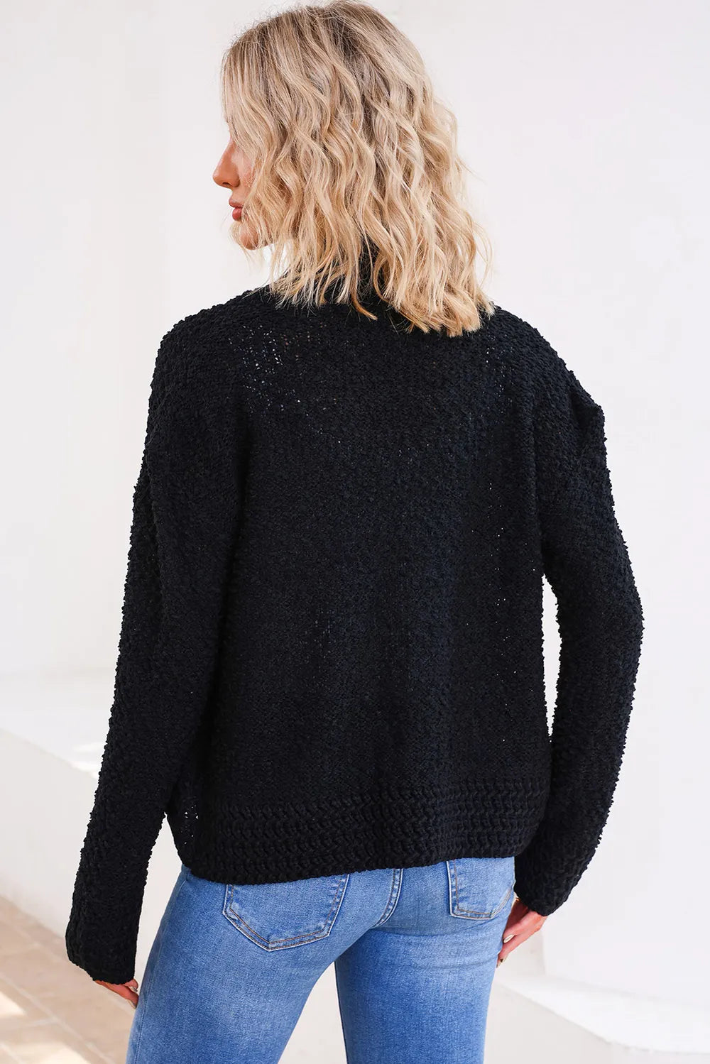 Black solid open-front cardigan shown from the back with textured knit finish
