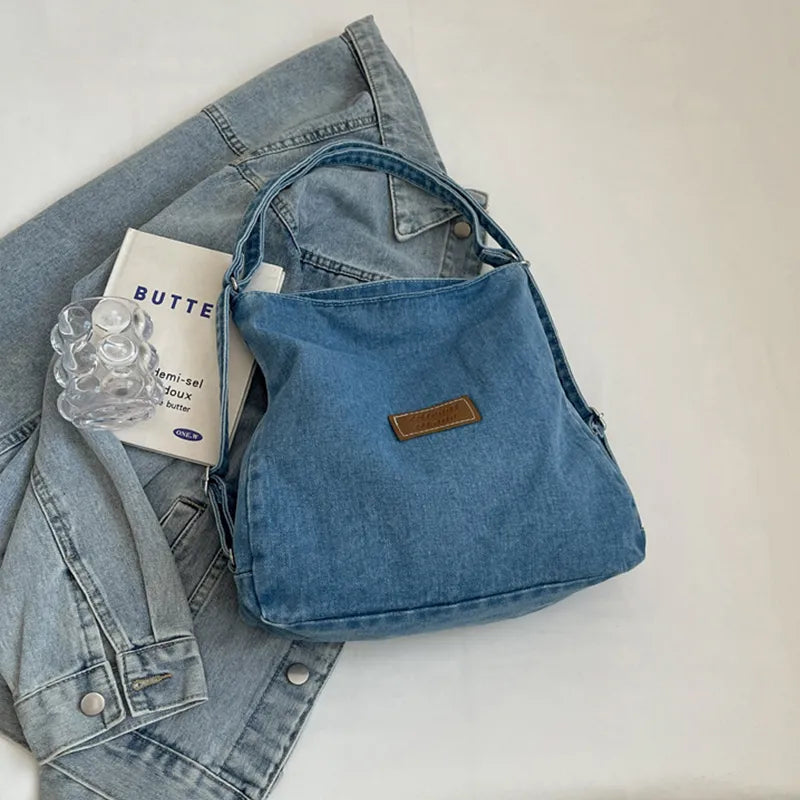 Denim shoulder bag with adjustable strap, blue fabric, brown logo patch and top zip