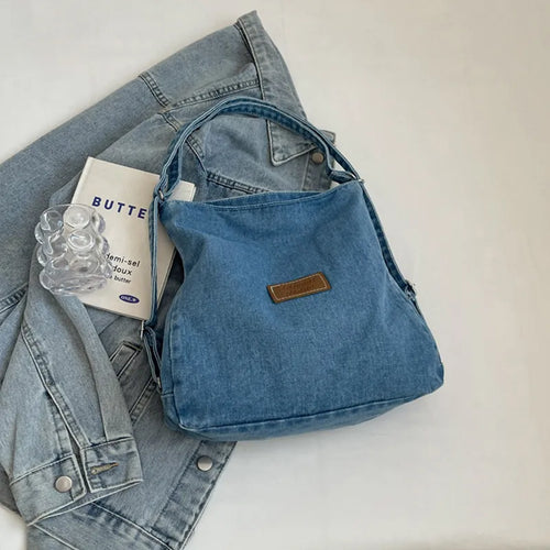 Denim shoulder bag with adjustable strap, blue fabric, brown logo patch and top zip