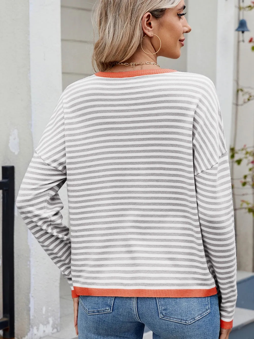 Striped contrast crewneck sweater, light gray and white stripes with orange rib trim, back view