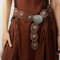 Dark brown vegan leather belt with silver oval buckle, eyelet studs, and patterned panels