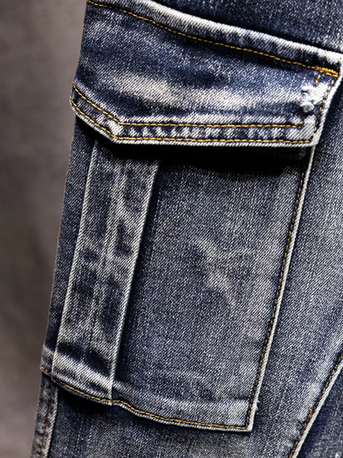 Men's medium-wash cotton jeans cargo pocket flap close-up with stitching