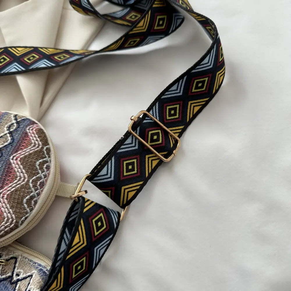 Patterned adjustable crossbody strap with gold buckle and geometric trim.