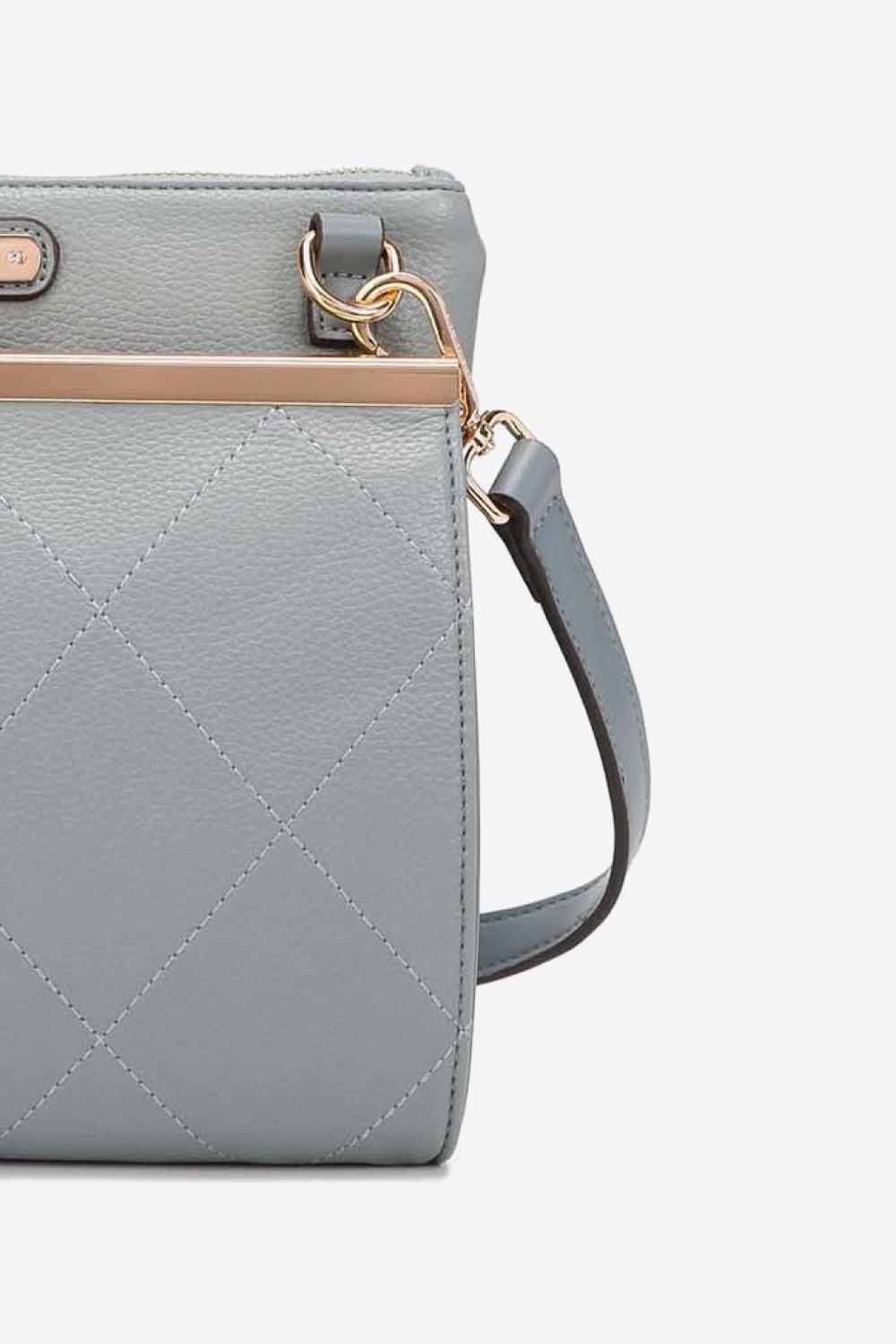 Light gray quilted handbag side with crossbody strap and gold tone ring hardware