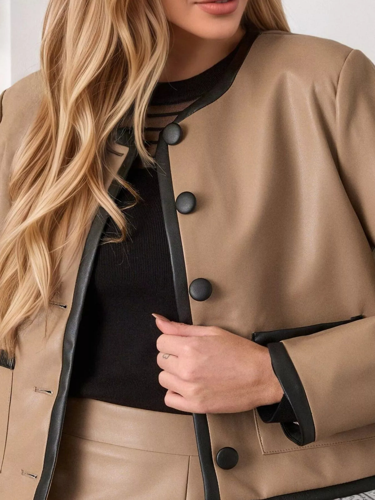 Tan jacket front with black contrast trim, snap buttons, and flap pockets