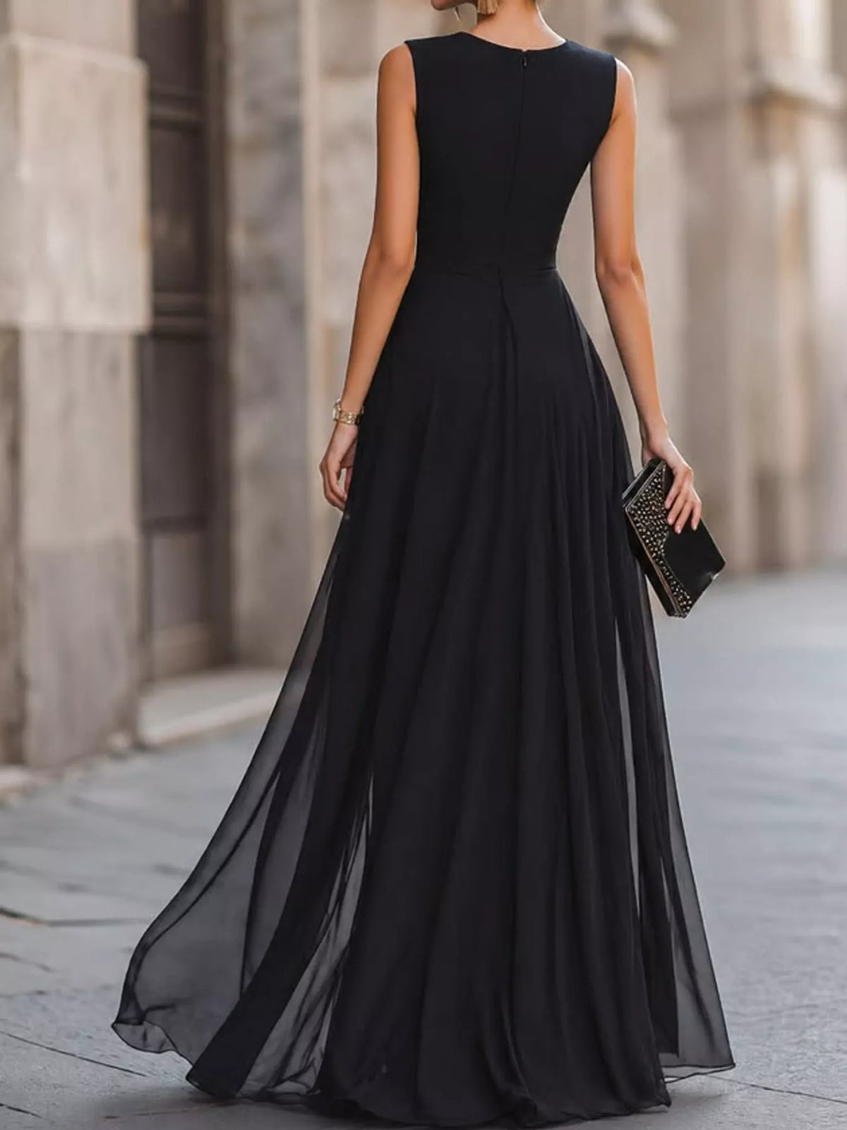 Black sleeveless maxi dress with fitted back, high slit, and layered flowing skirt.