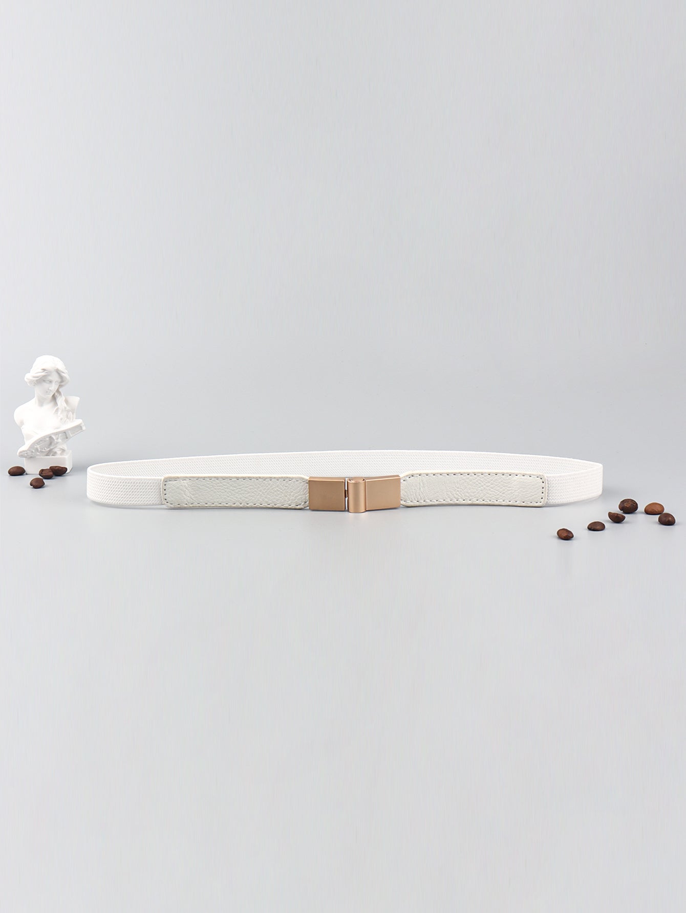 Elastic vegan leather skinny belt, white with rose-gold buckle, flat lay