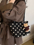 Black suede shoulder handbag with white polka dots and dangling cat accessory charm