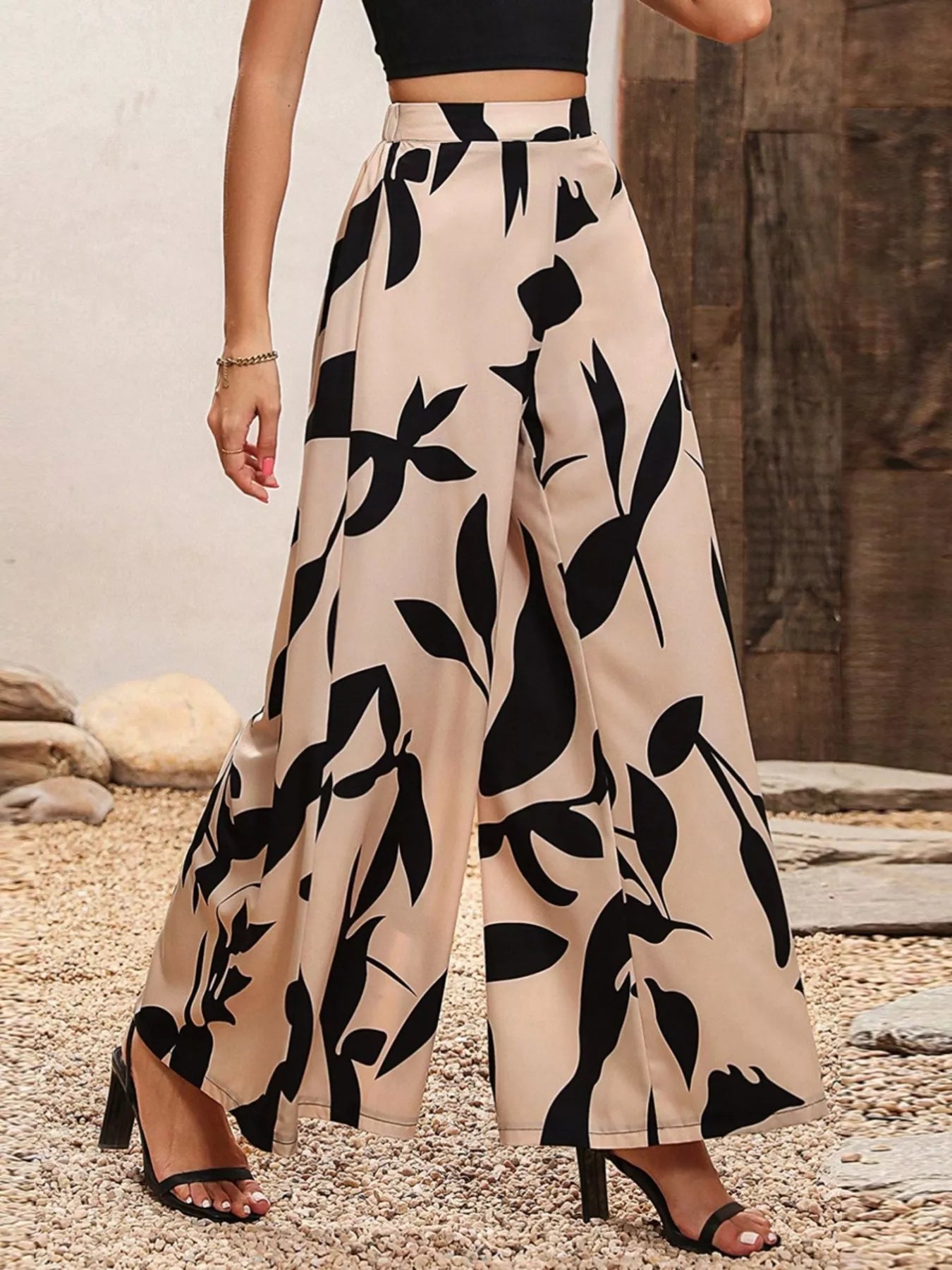 Printed wide-leg pants, tan and black abstract leaf design, long flowy silhouette.
