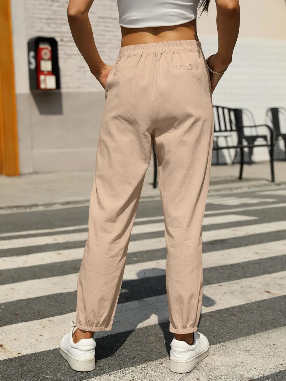 Beige elastic waist tapered pants with drawstring, loose fit through the thighs