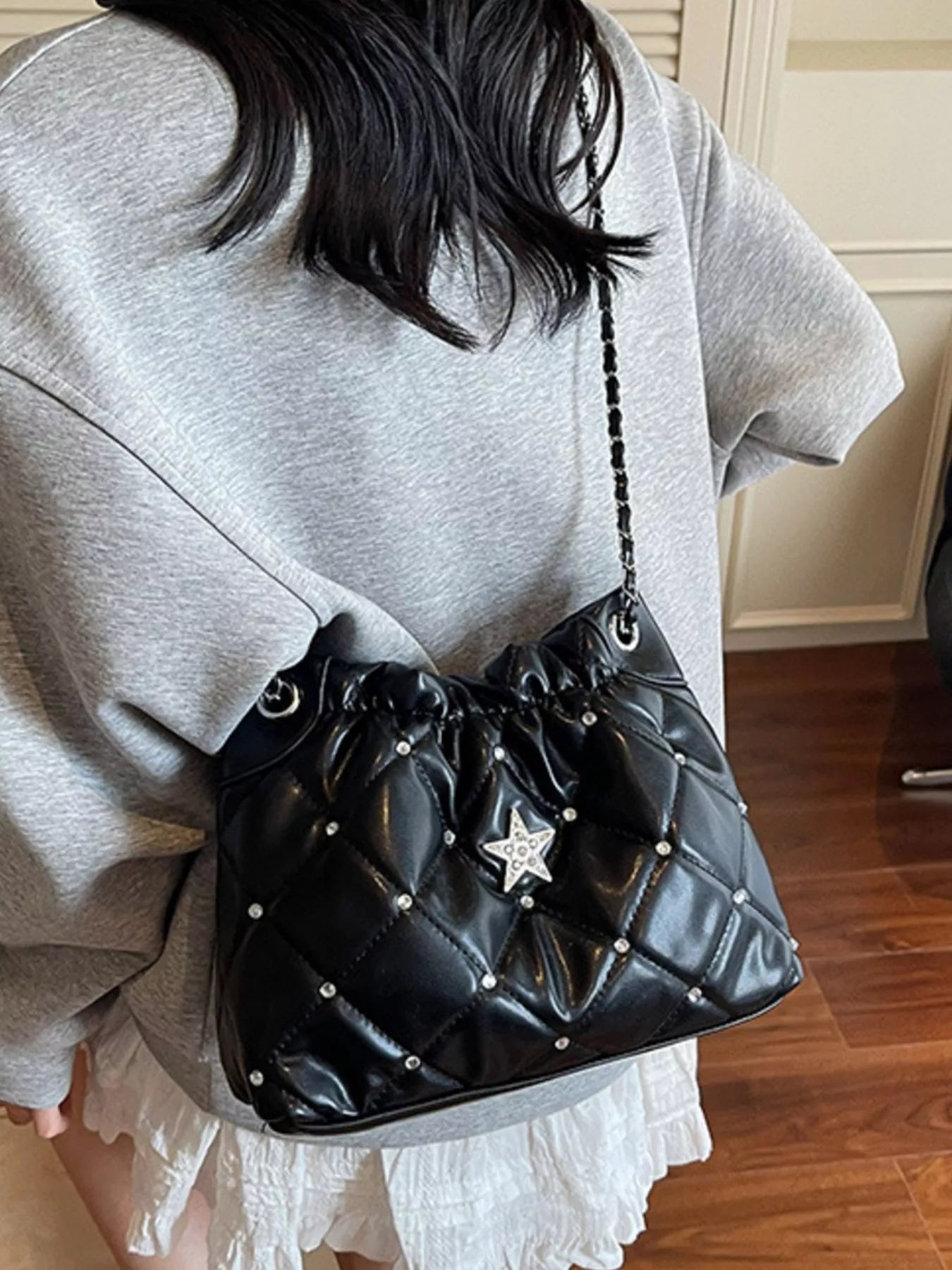 Quilted black PU shoulder bag with rhinestone star decor and chain strap.