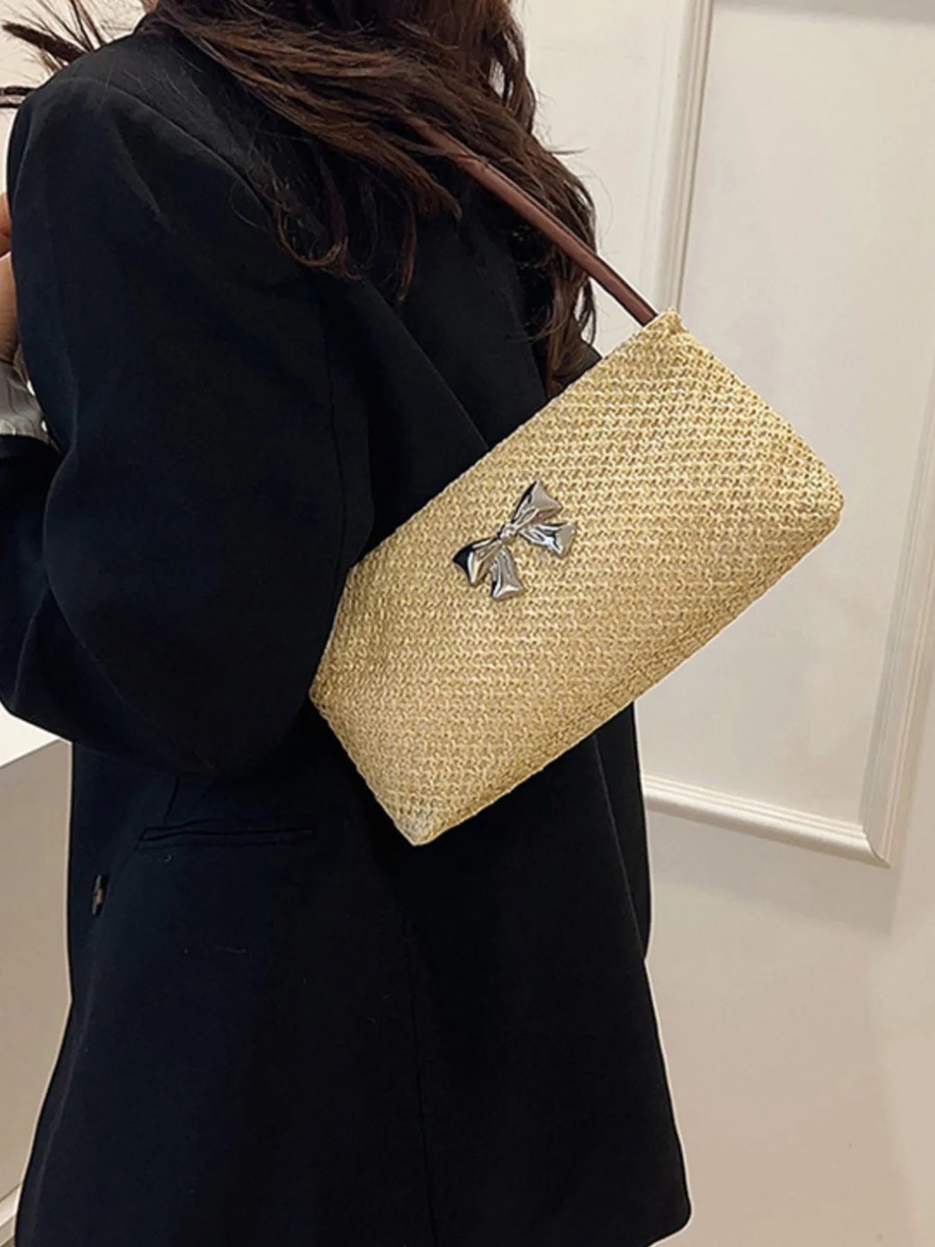 Woven straw shoulder bag with silver bow detail and brown strap, tan woven finish