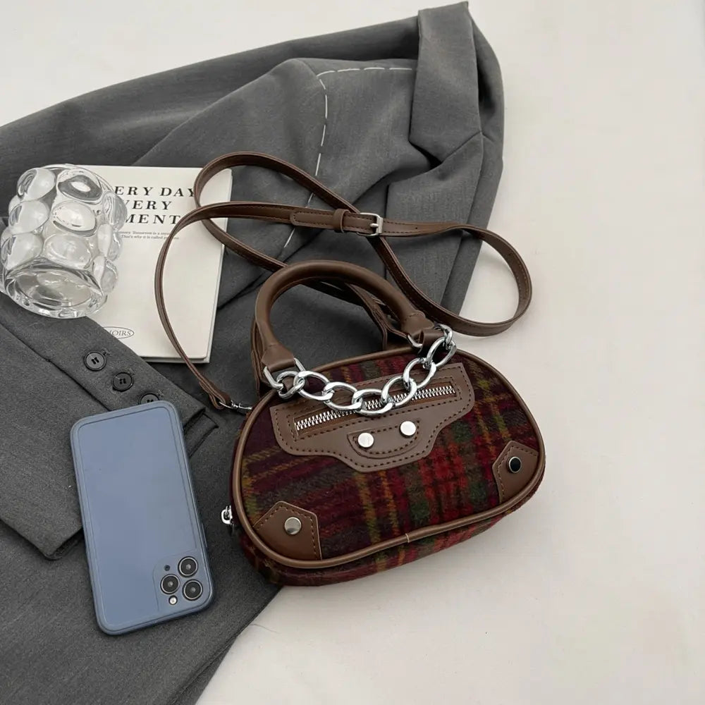 Plaid crossbody bag with brown leather trim, zipper top, and silver chain strap