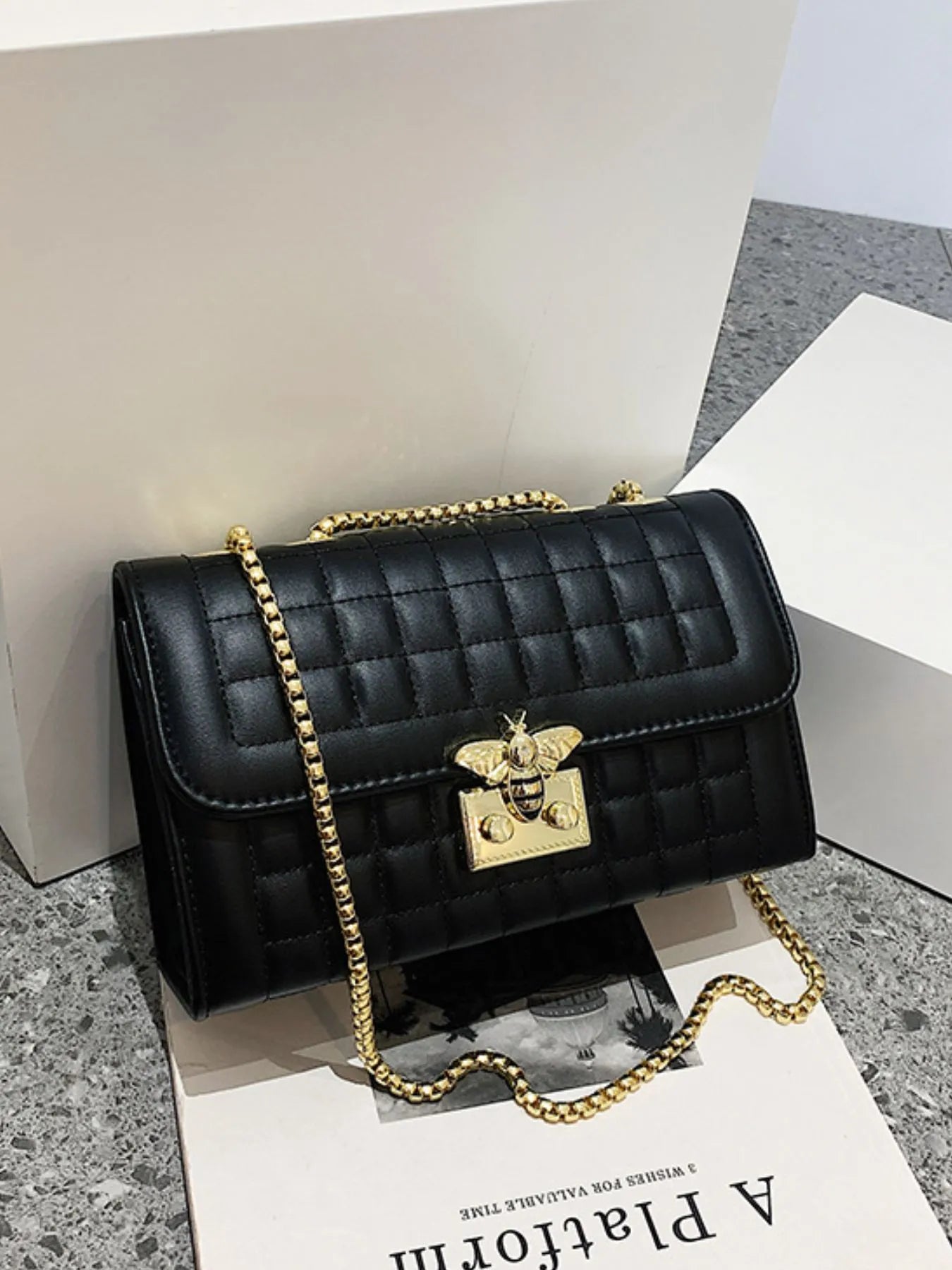 Black quilted shoulder bag with gold chain, bee detail on front flap