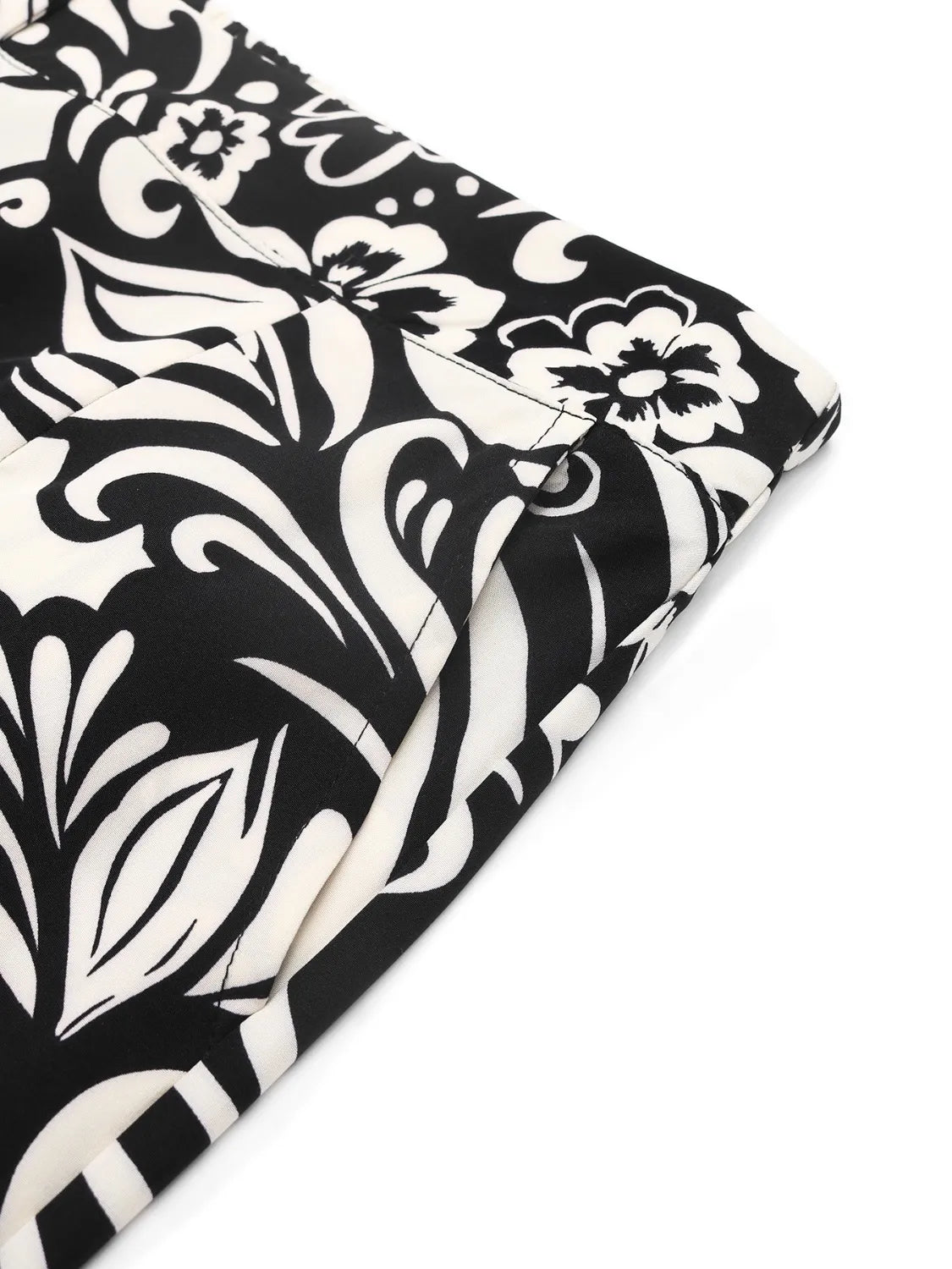 Close-up fabric of wide-leg pants: black background with white paisley floral pattern