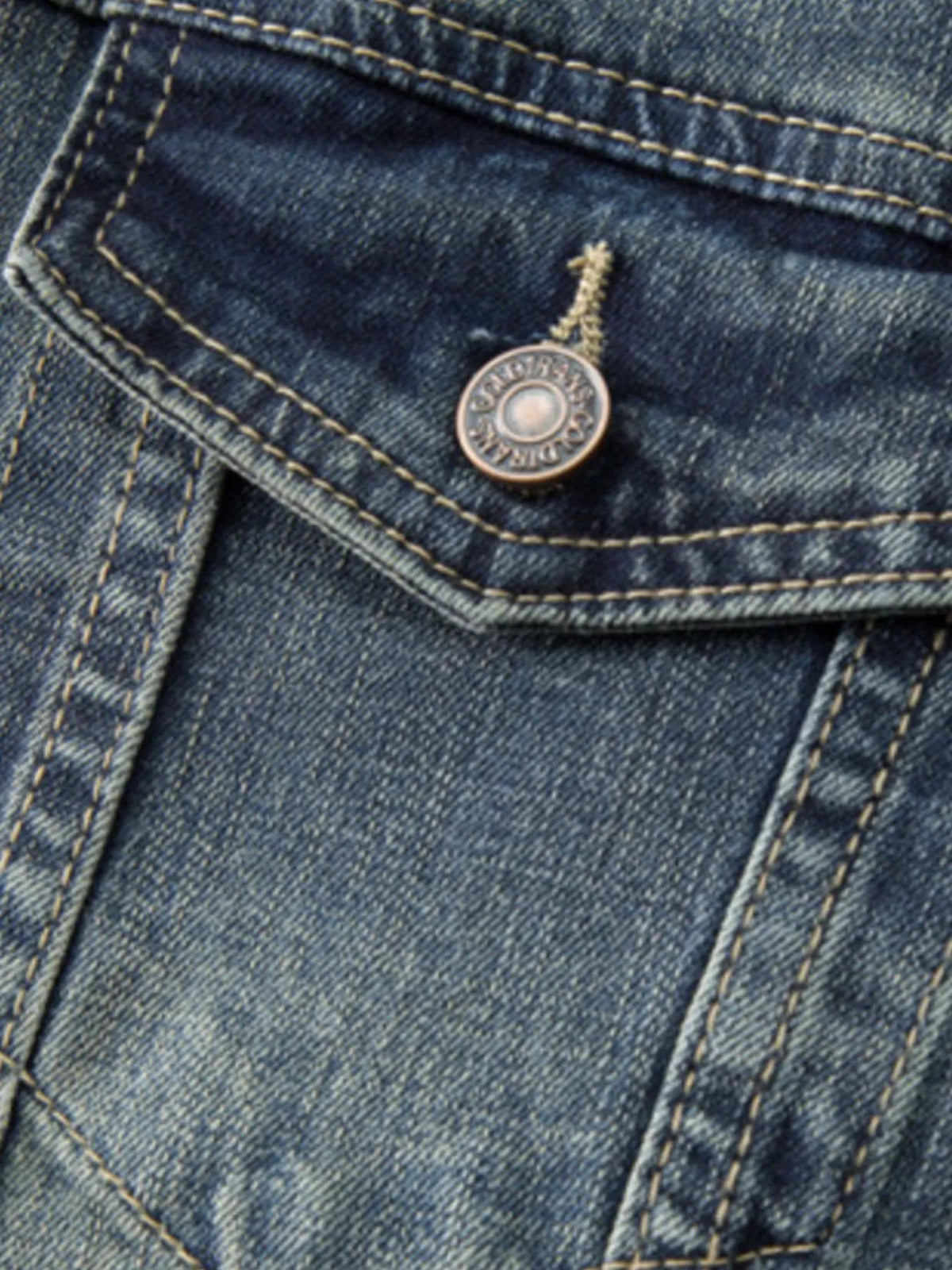 Dark wash denim jacket close-up: metal snap button with rivet detail