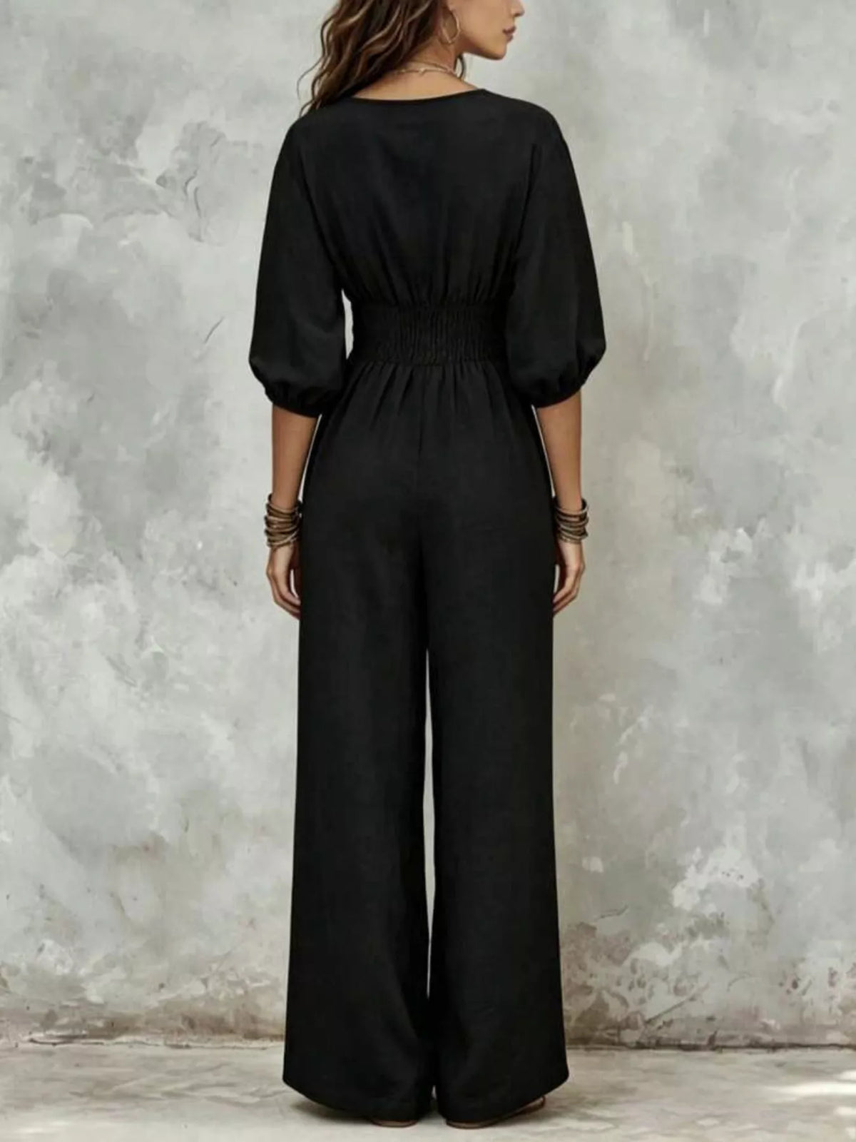 Black wide-leg jumpsuit with smocked waist and three-quarter puff sleeves