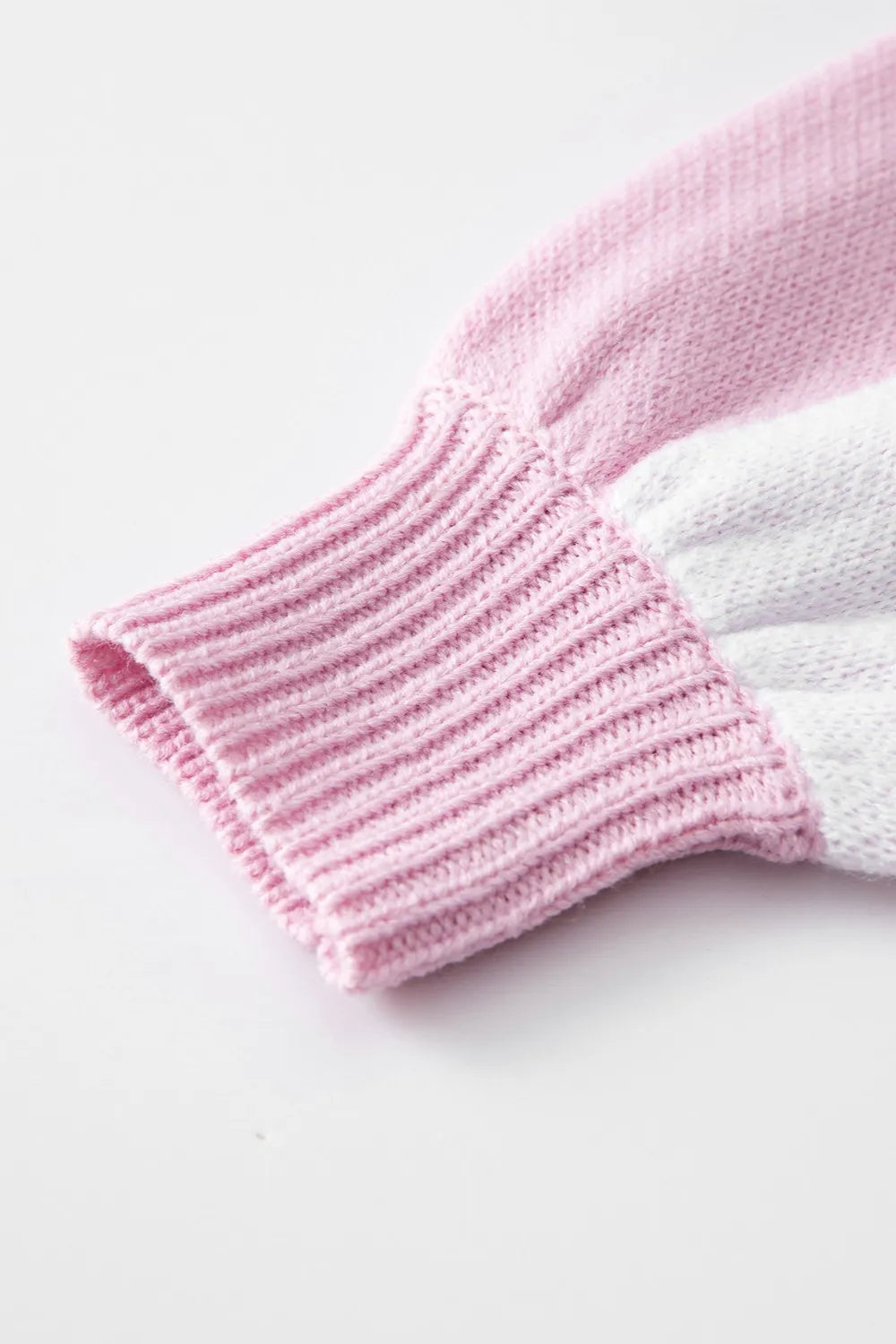 Ribbed striped knit cuff on a pink and white checkered sweater sleeve.