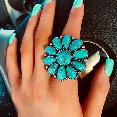 Turquoise flower-shaped alloy ring with oval turquoise stones, worn on finger