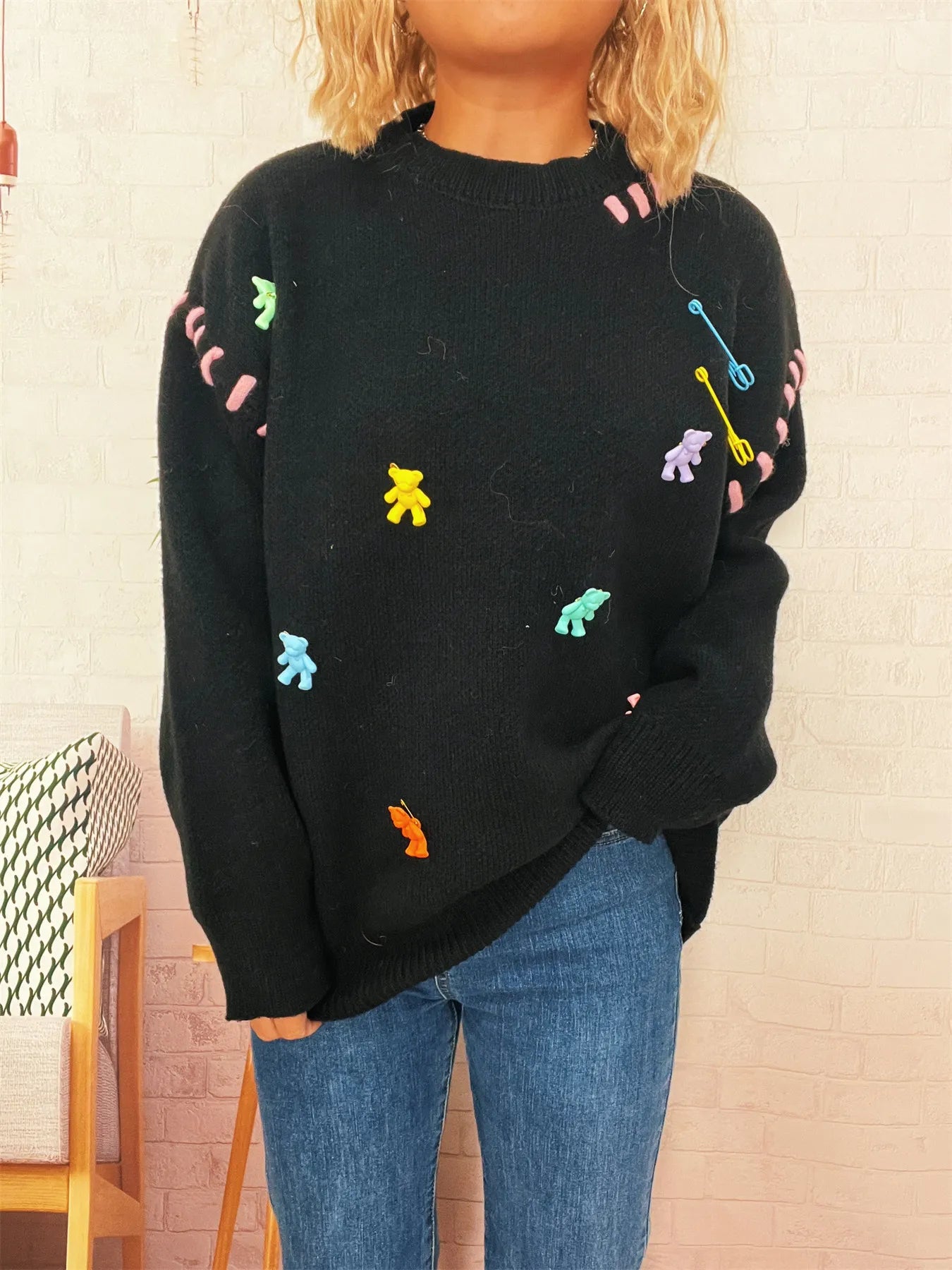 Black round-neck knit sweater with colorful animal/applique graphics on chest and sleeves