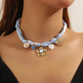 Light blue ribbon necklace with floral charm, pearl bead, and star-shaped pendants