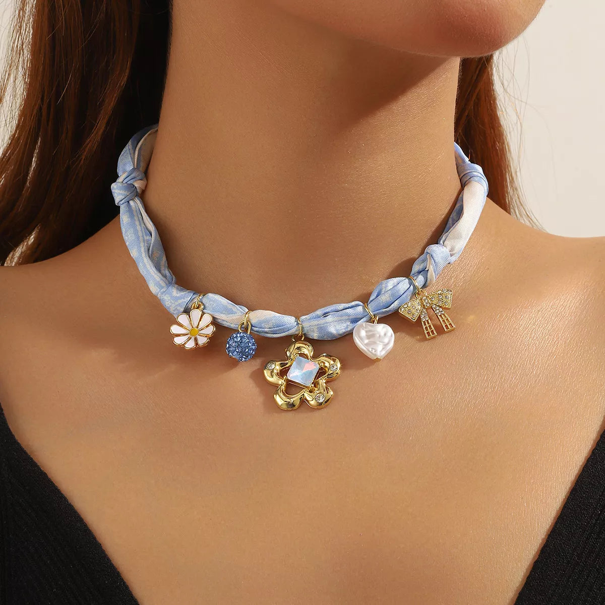 Light blue ribbon necklace with floral charm, pearl bead, and star-shaped pendants