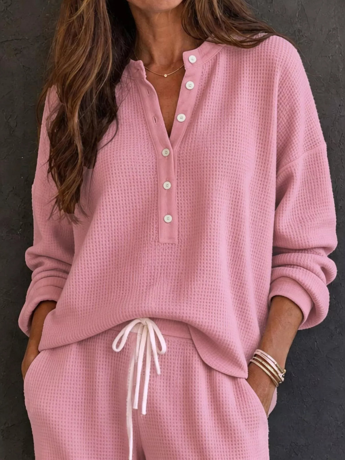 Pink waffle-knit henley pullover with front buttons and tied-waist pants.