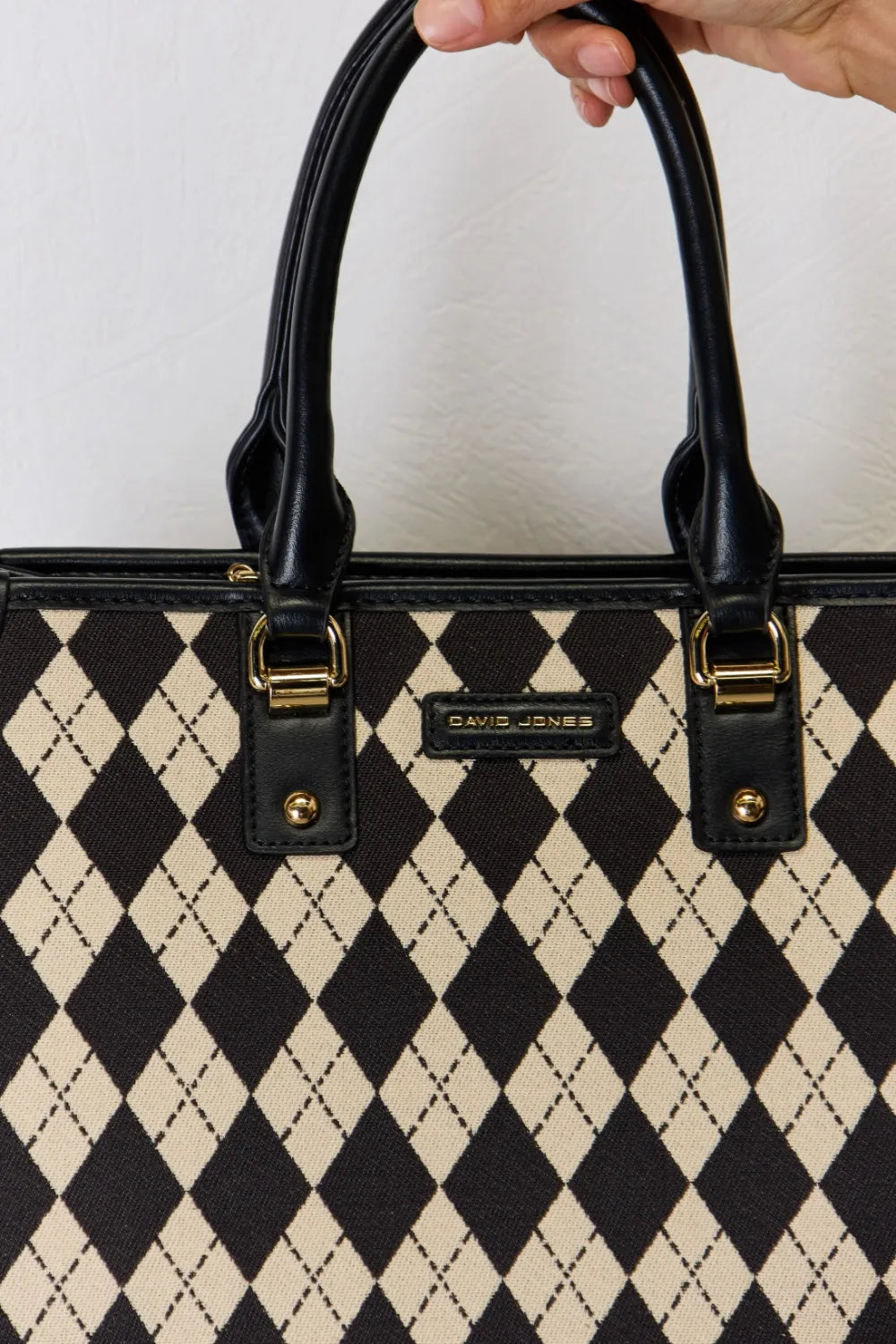 Argyle-pattern PU leather handbag front detail with gold-tone logo plate and strap hardware