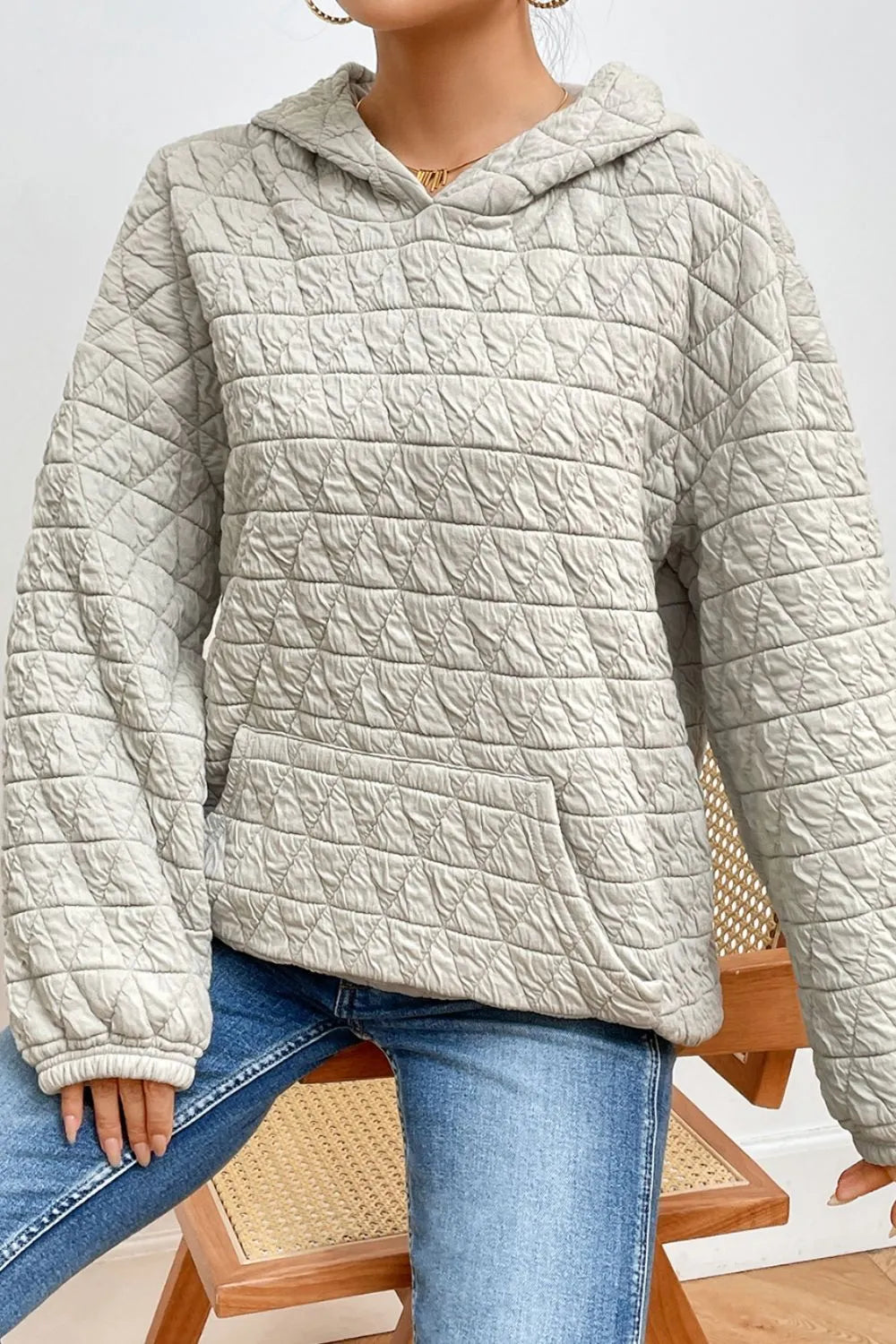 Light gray quilted long-sleeve hoodie with hood and kangaroo pocket detail