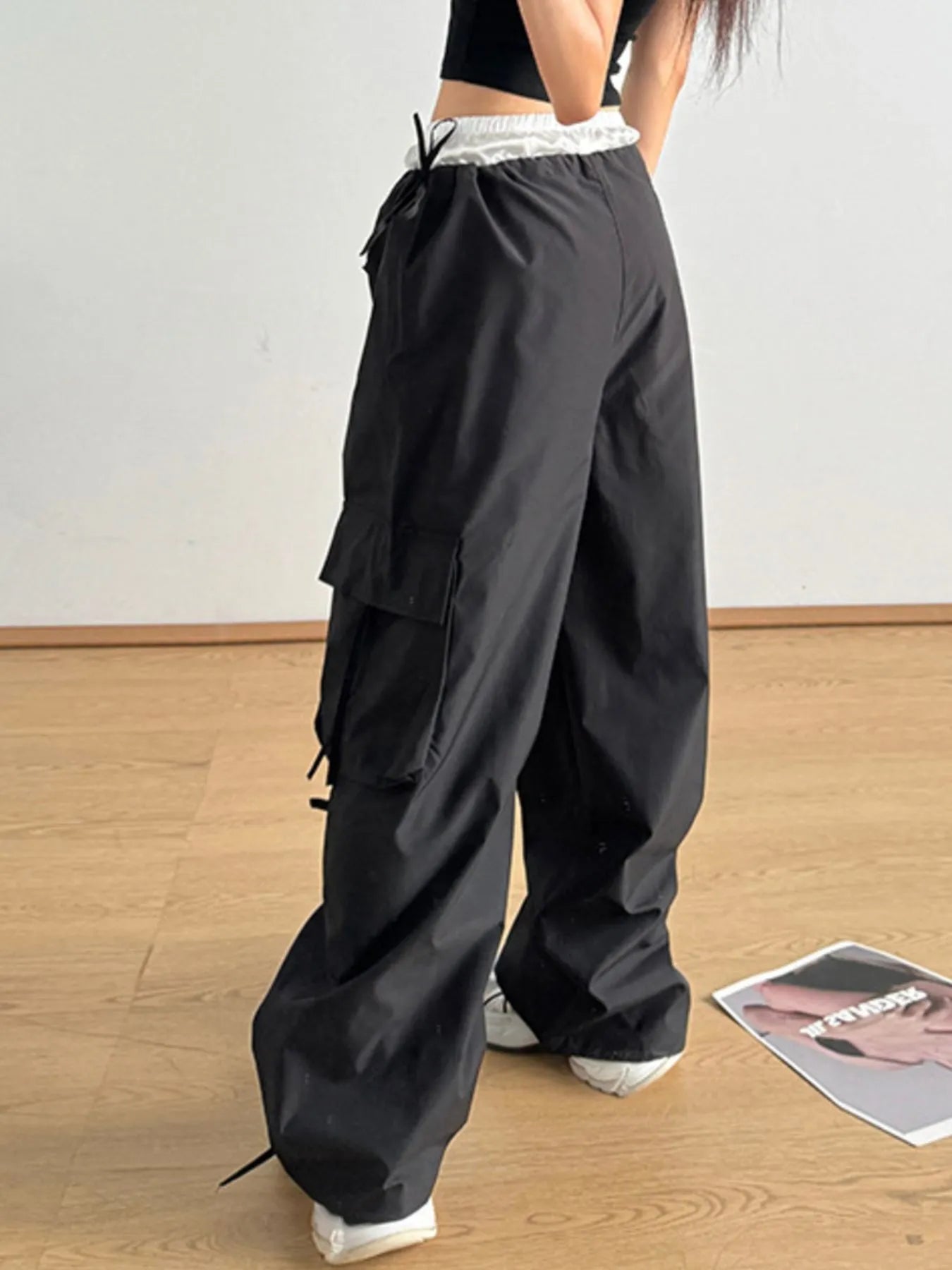 Black cargo pants with elastic waist, side bows, flap pockets, loose wide legs