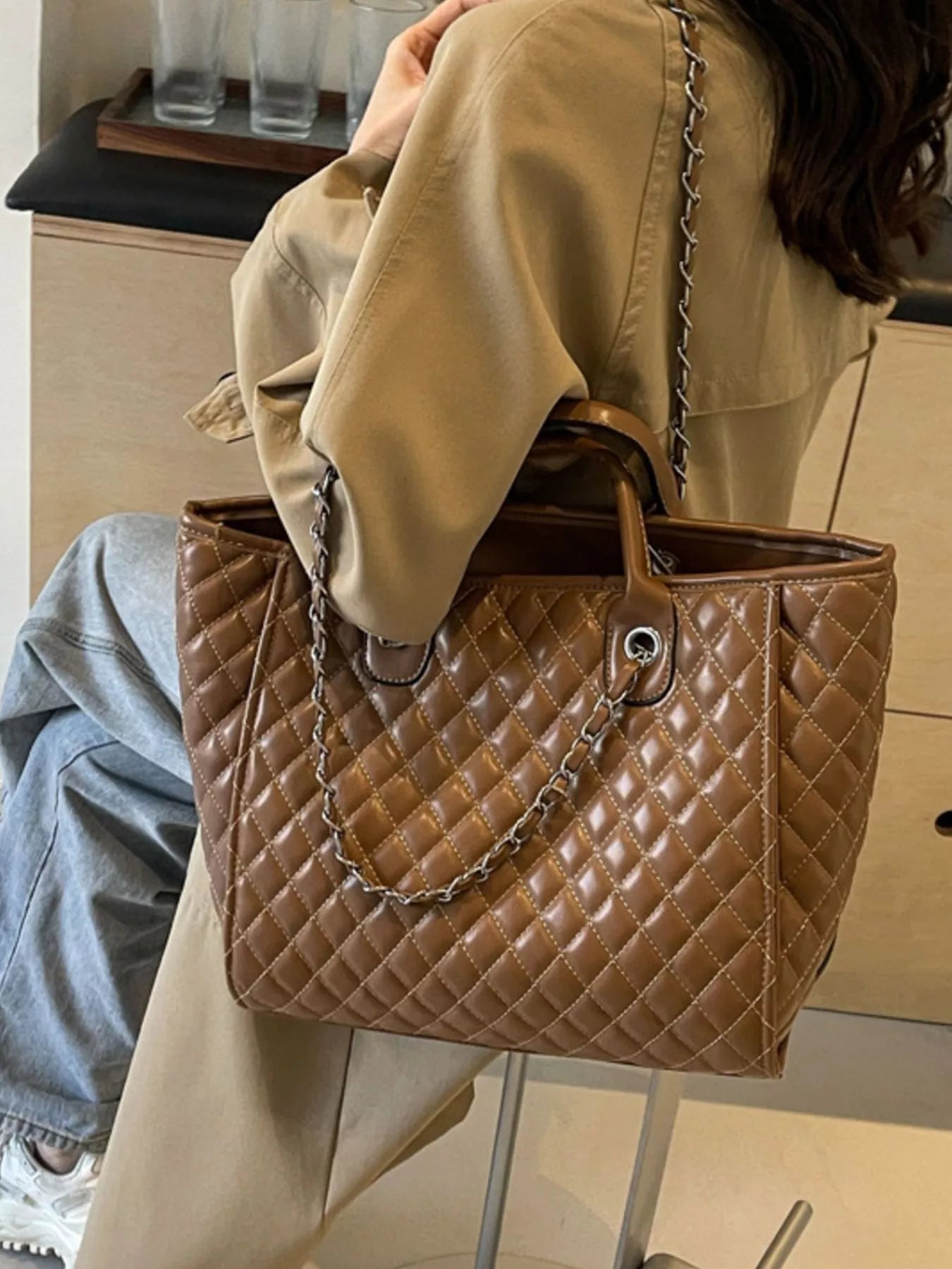 Brown quilted medium tote-style bag with chain shoulder strap and circular ring details