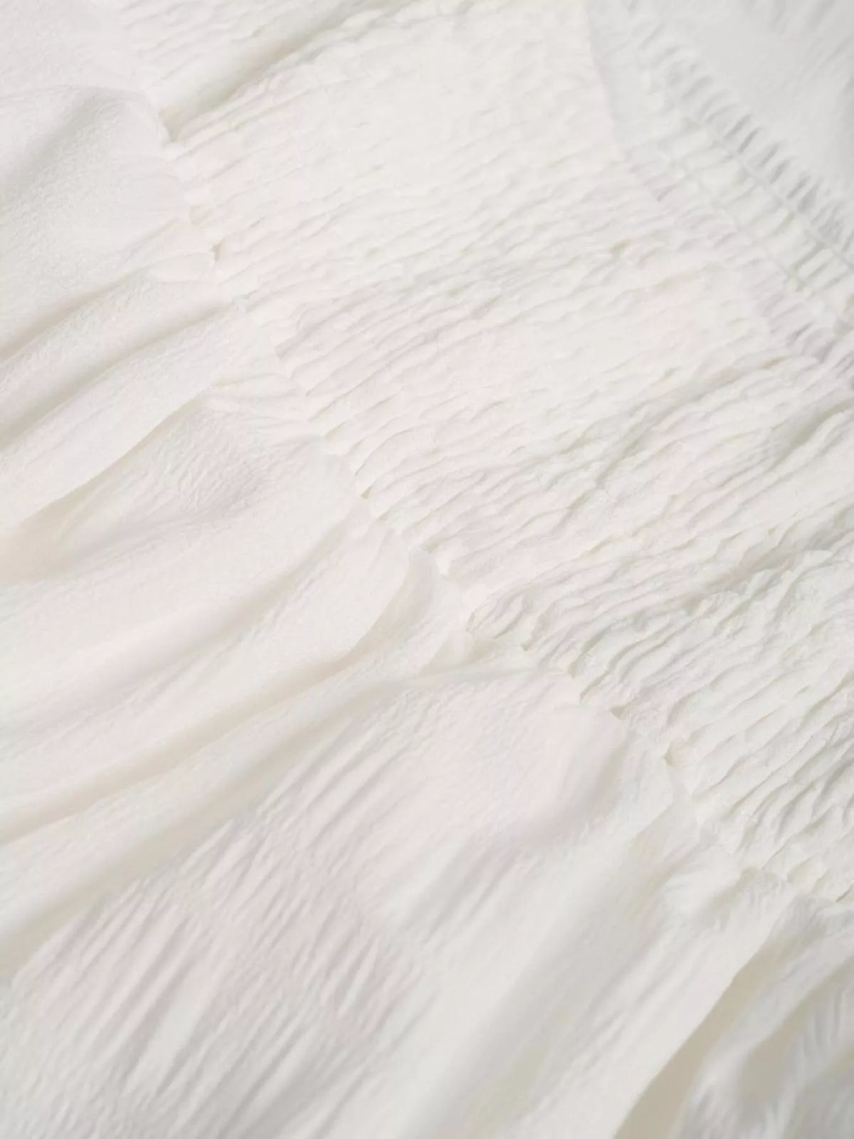 White tiered skirt fabric close-up with ruched texture and gathered ruffle layers
