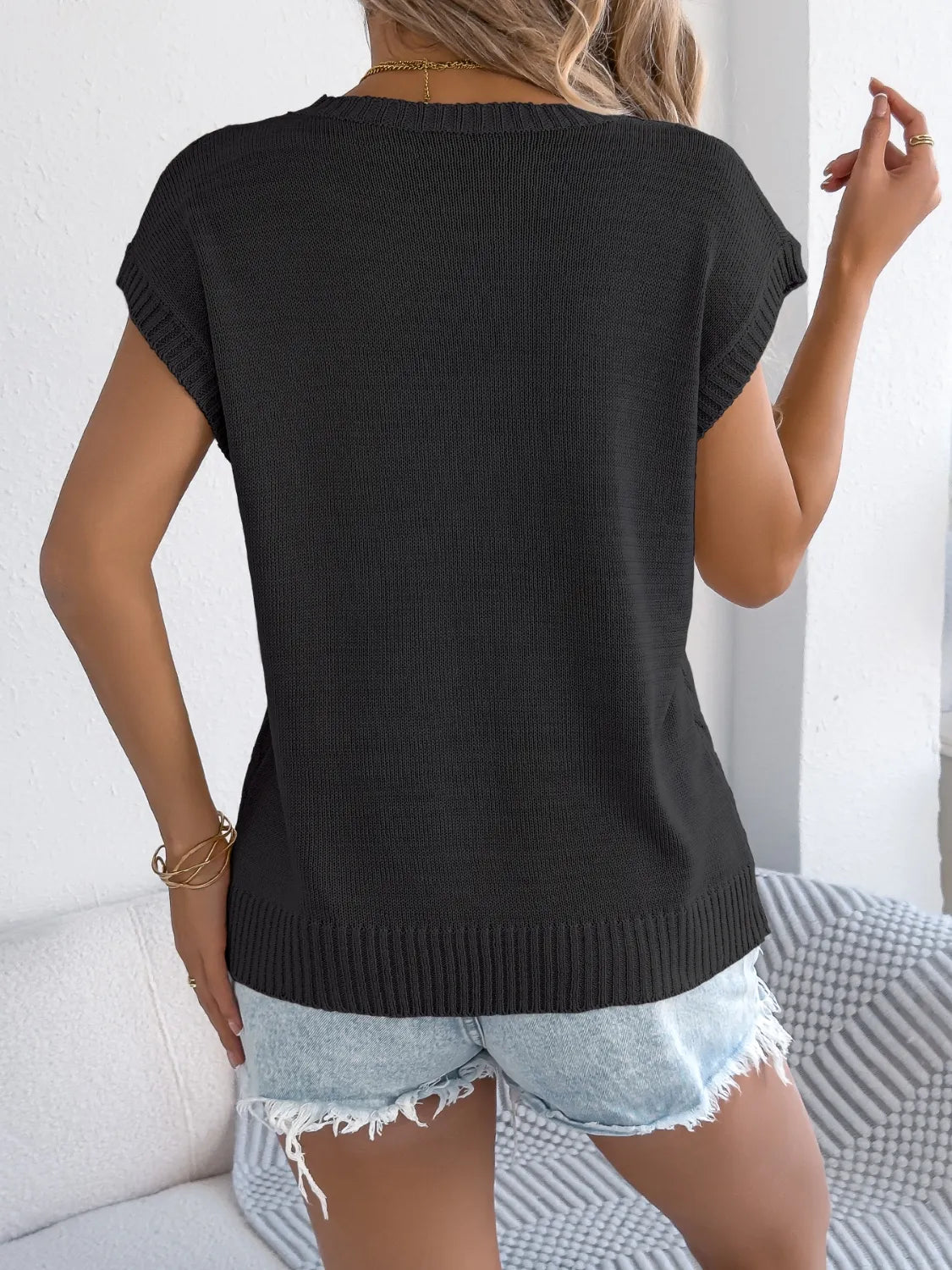 Back view of black cable-knit round neck knit top with short sleeves
