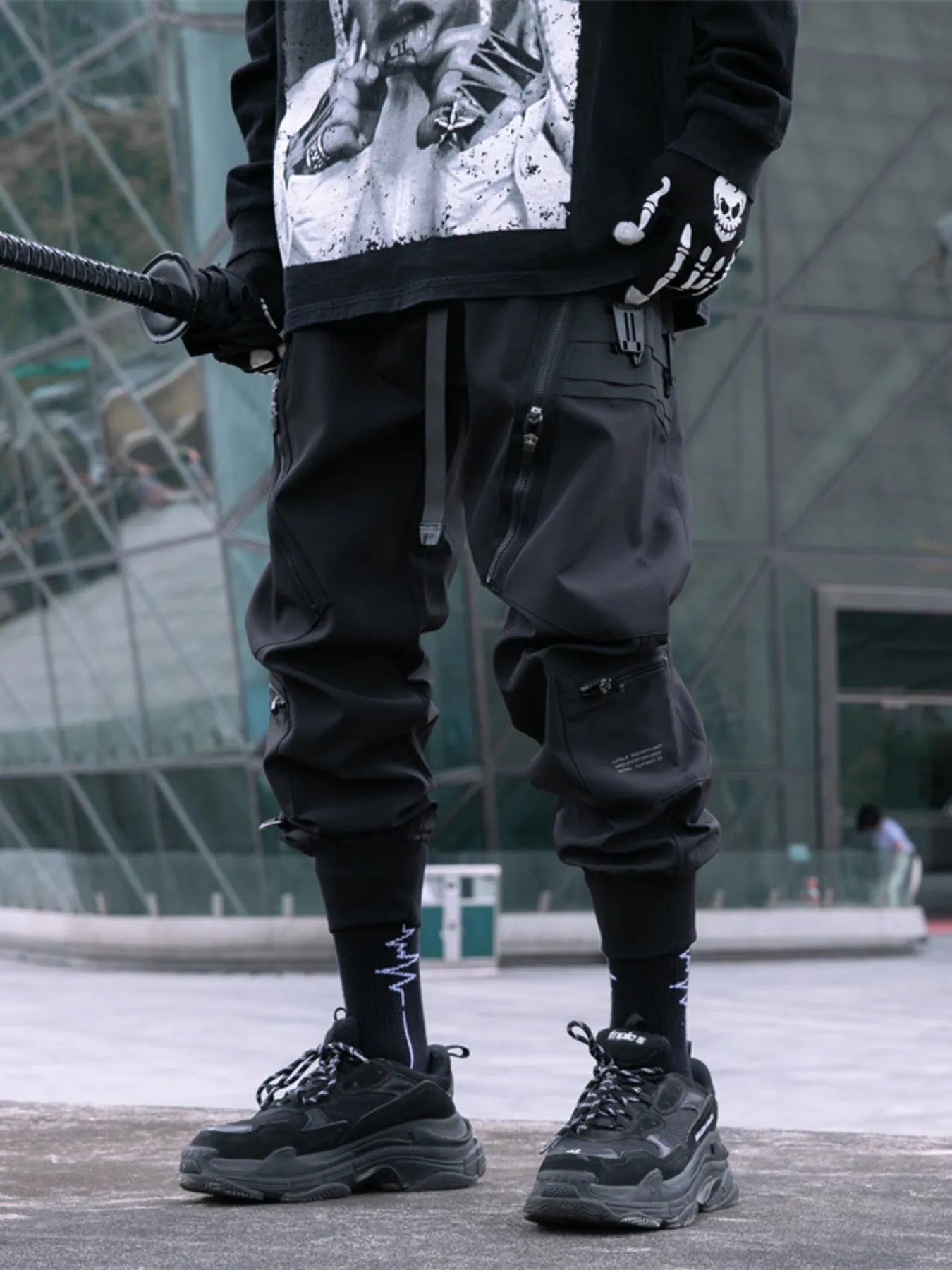 Black cargo joggers on model with cargo pockets, cuffed ankles, and zip details