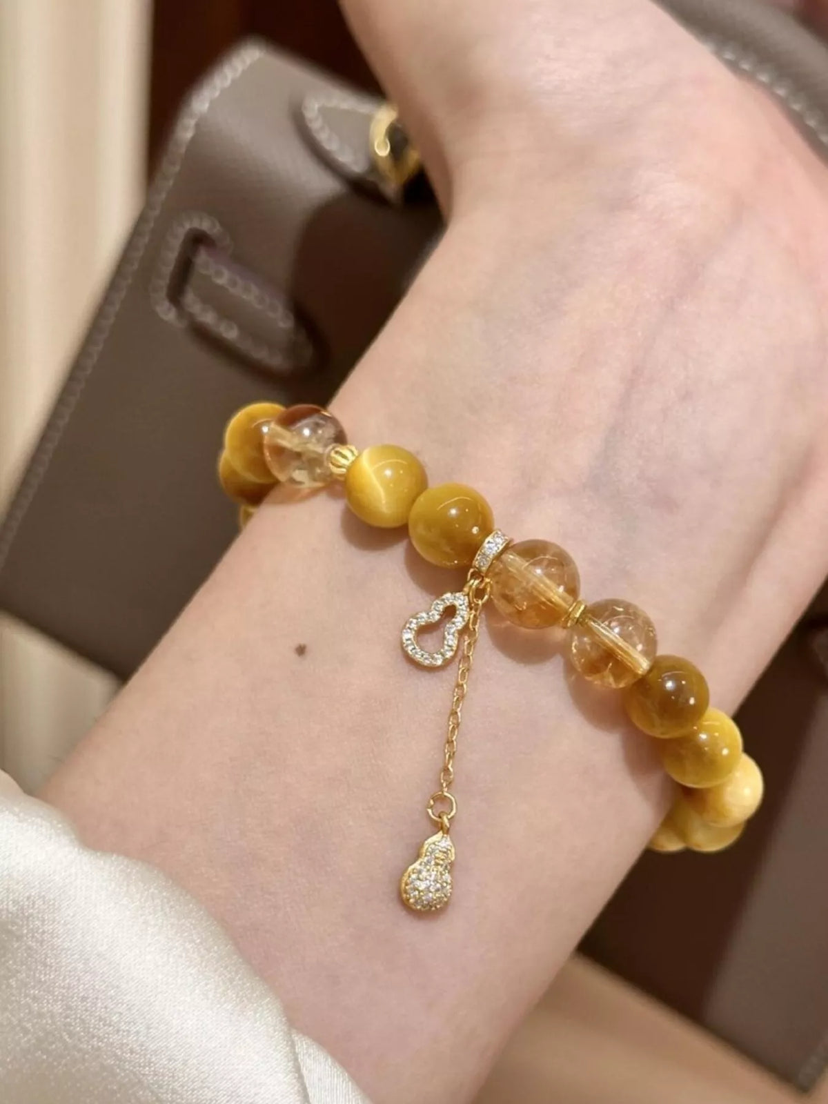 Beaded bracelet wrist close-up, amber beads with dangling gourd charm