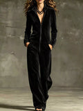 Black velour zip-up jumpsuit with pockets, long sleeves, and wide-leg pants