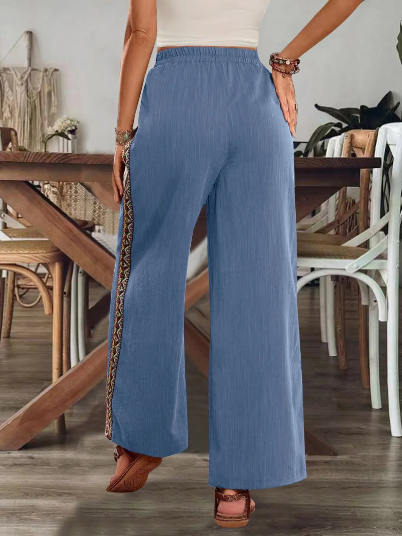 Blue bohemian wide-leg pants with elastic waist and colorful embroidered side stripe.