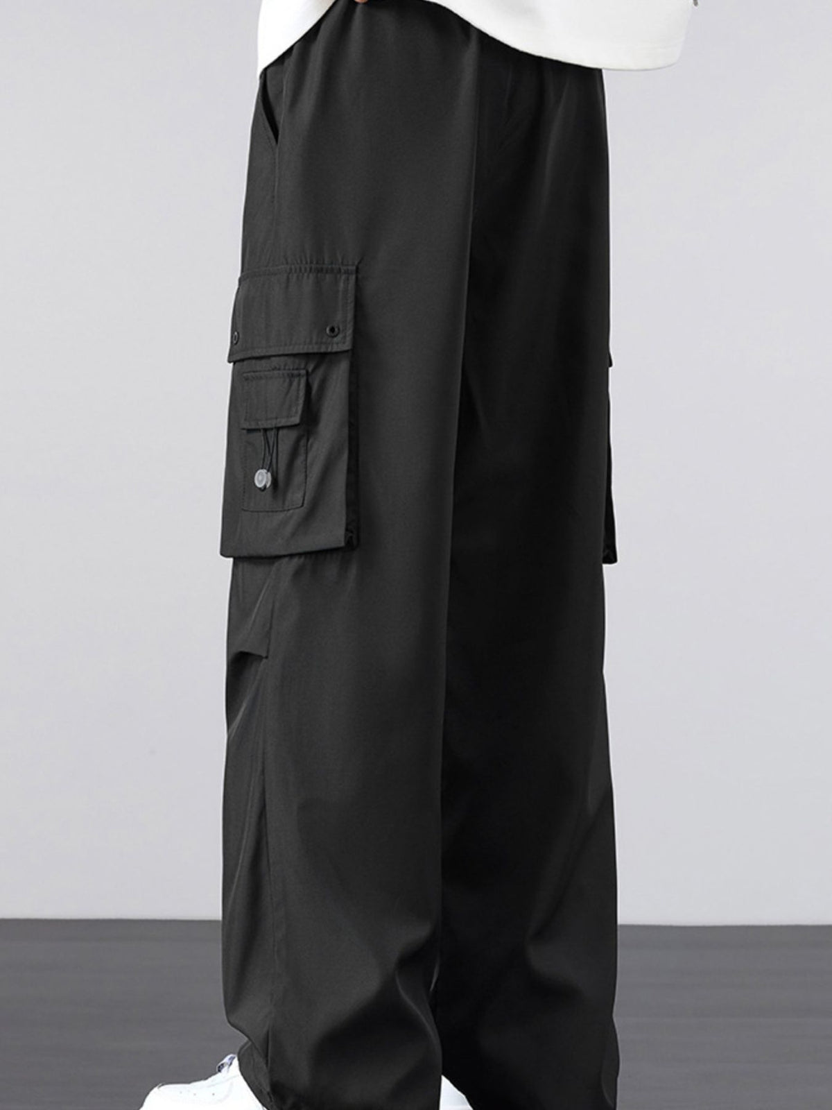 Black cargo pants with drawstring waist and thigh flap cargo pocket detail