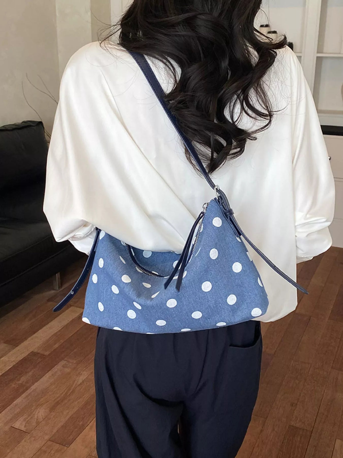 Small blue polka dot crossbody bag on shoulder with adjustable strap