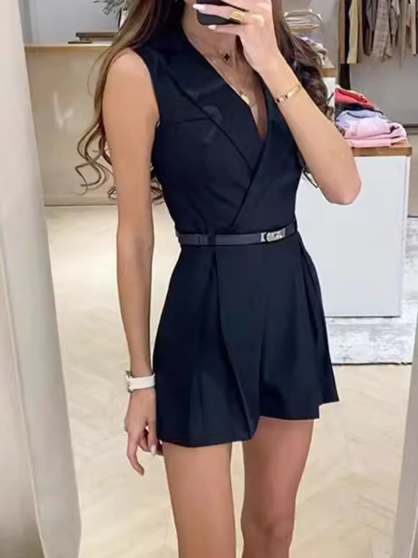 Navy sleeveless surplice romper with V-neck and buckle belt, tailored pleats