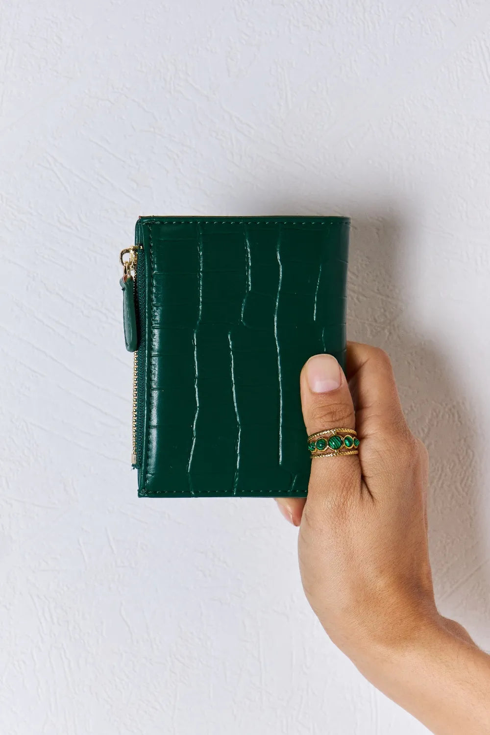 Green textured vegan leather mini wallet with gold-tone zipper and front seam detail