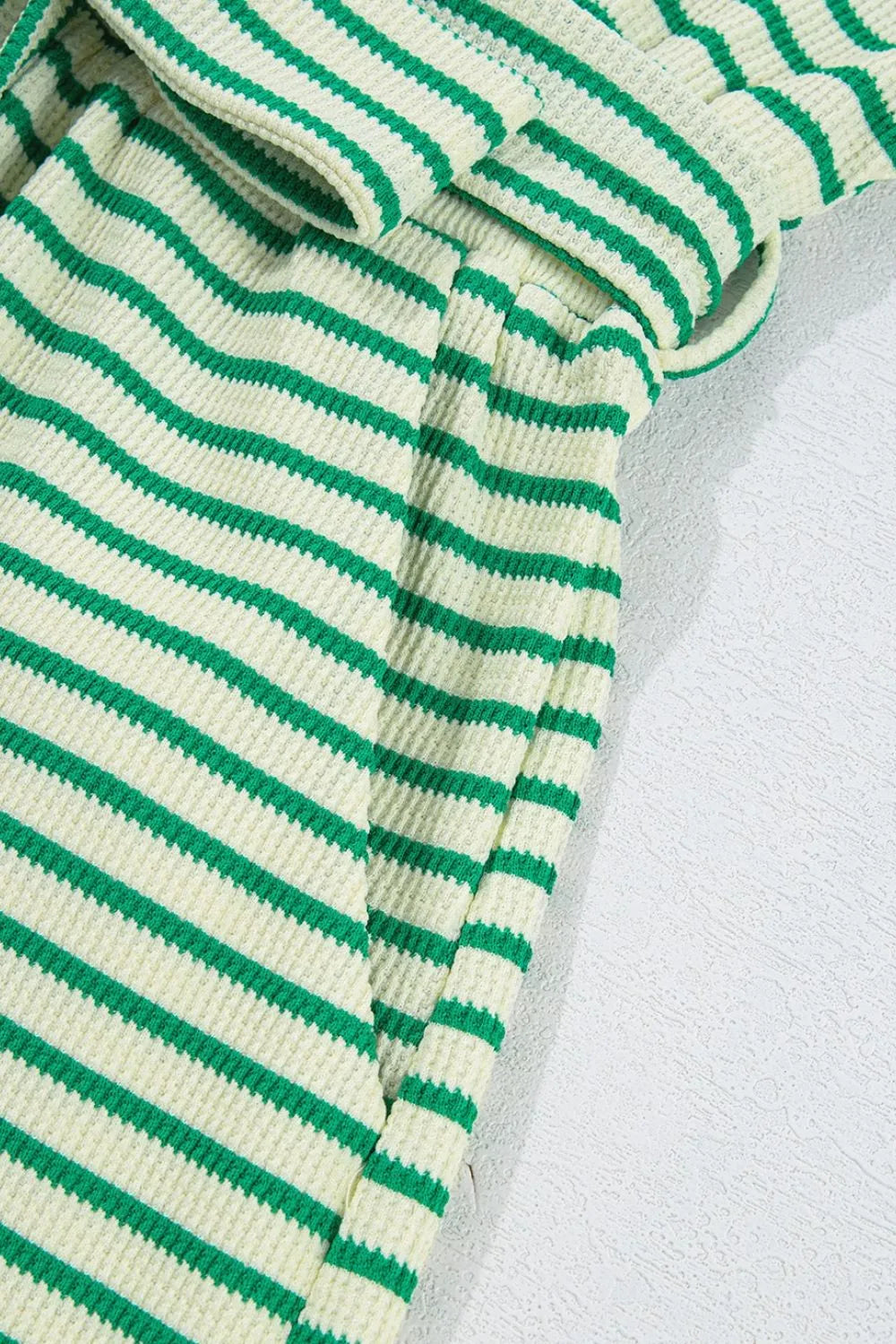 Close-up of green and white striped knit fabric with stitched seams