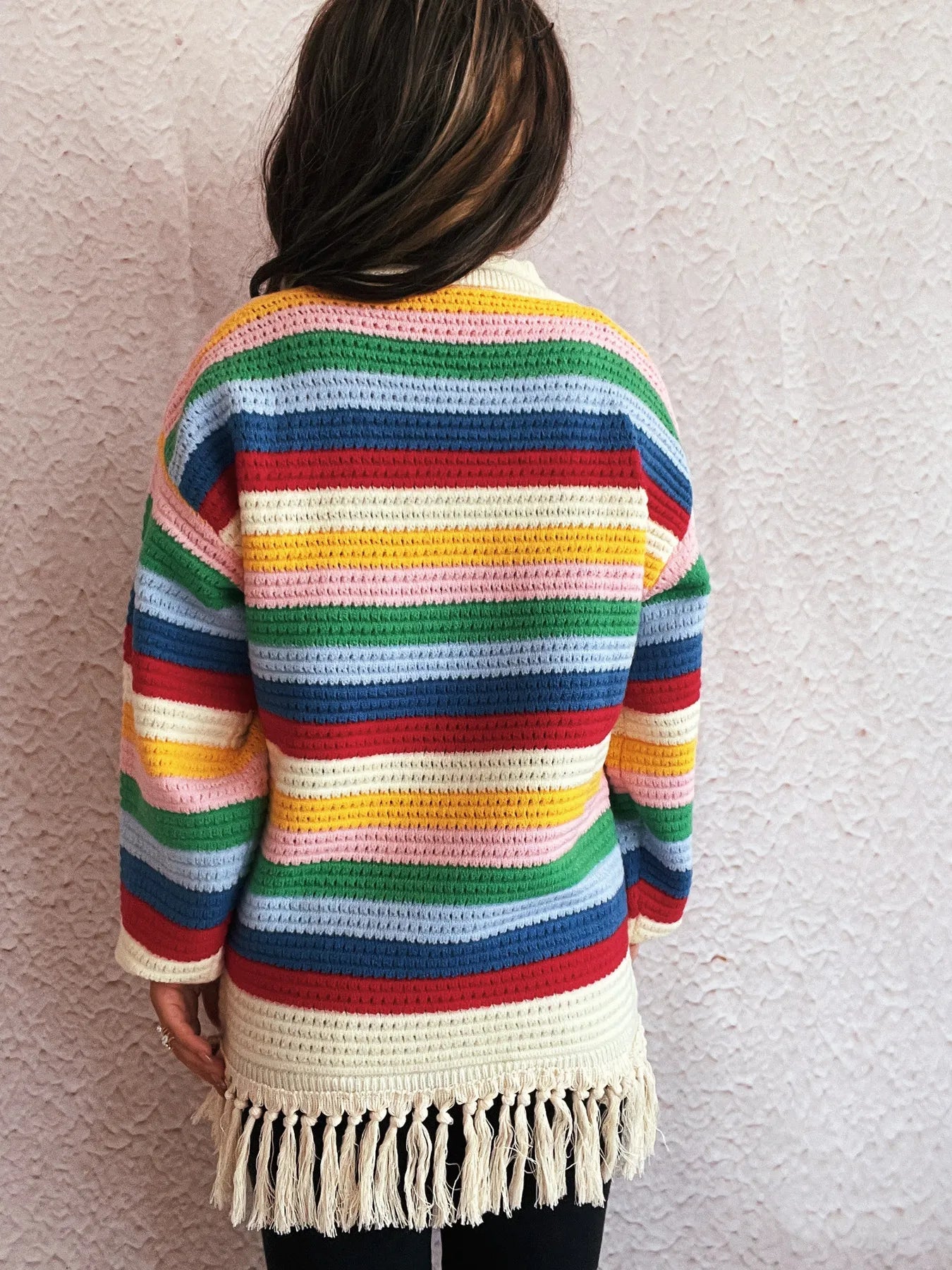 Back view of rainbow striped long sleeve sweater with cream collar and tassel hem
