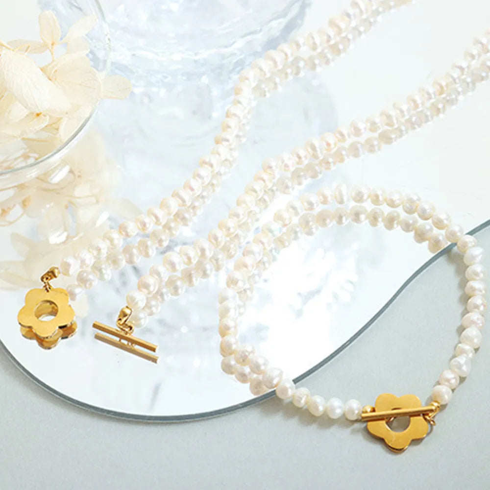 Pearl bead bracelet flat lay with gold flower and bar clasp detail