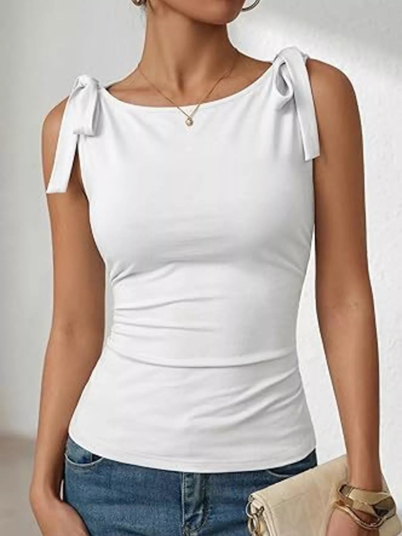 White tie-shoulder tank top with bow straps and scoop neckline.