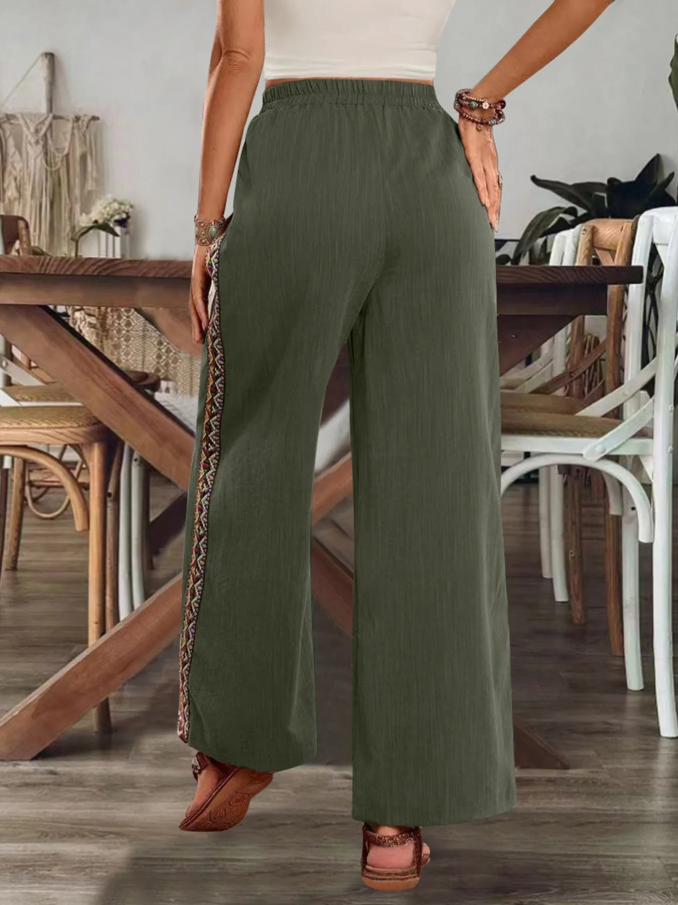Olive green bohemian wide-leg pants with elastic waistband and embroidered side stripe.
