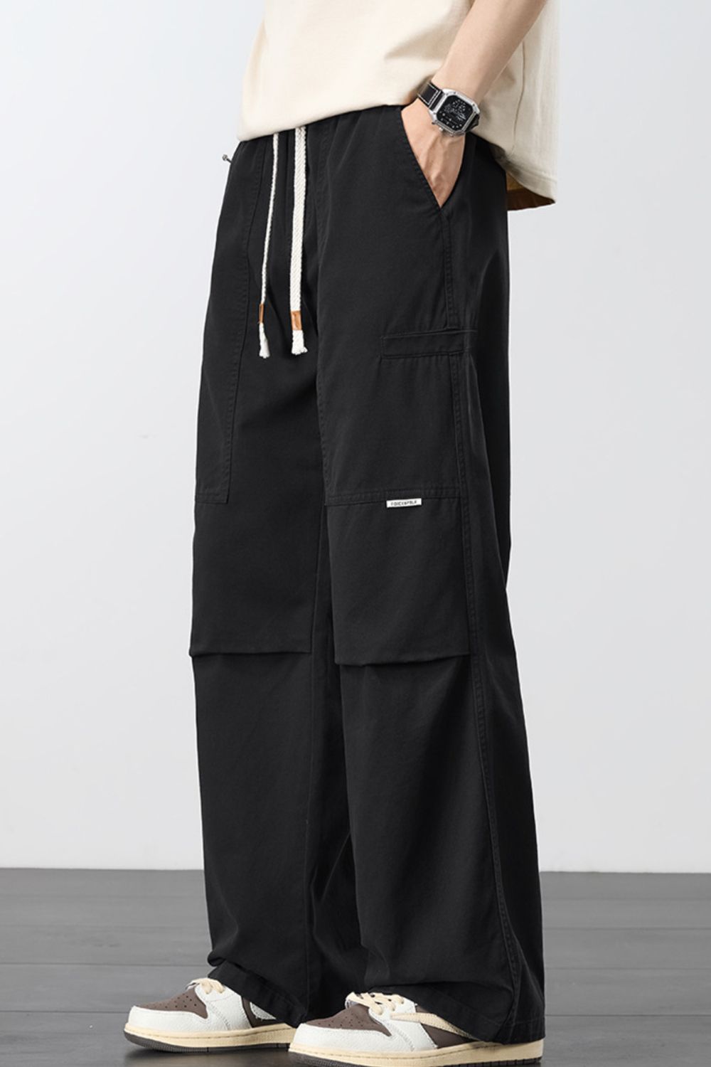 Black loose cargo pants with drawstring waist and front flap cargo pocket.