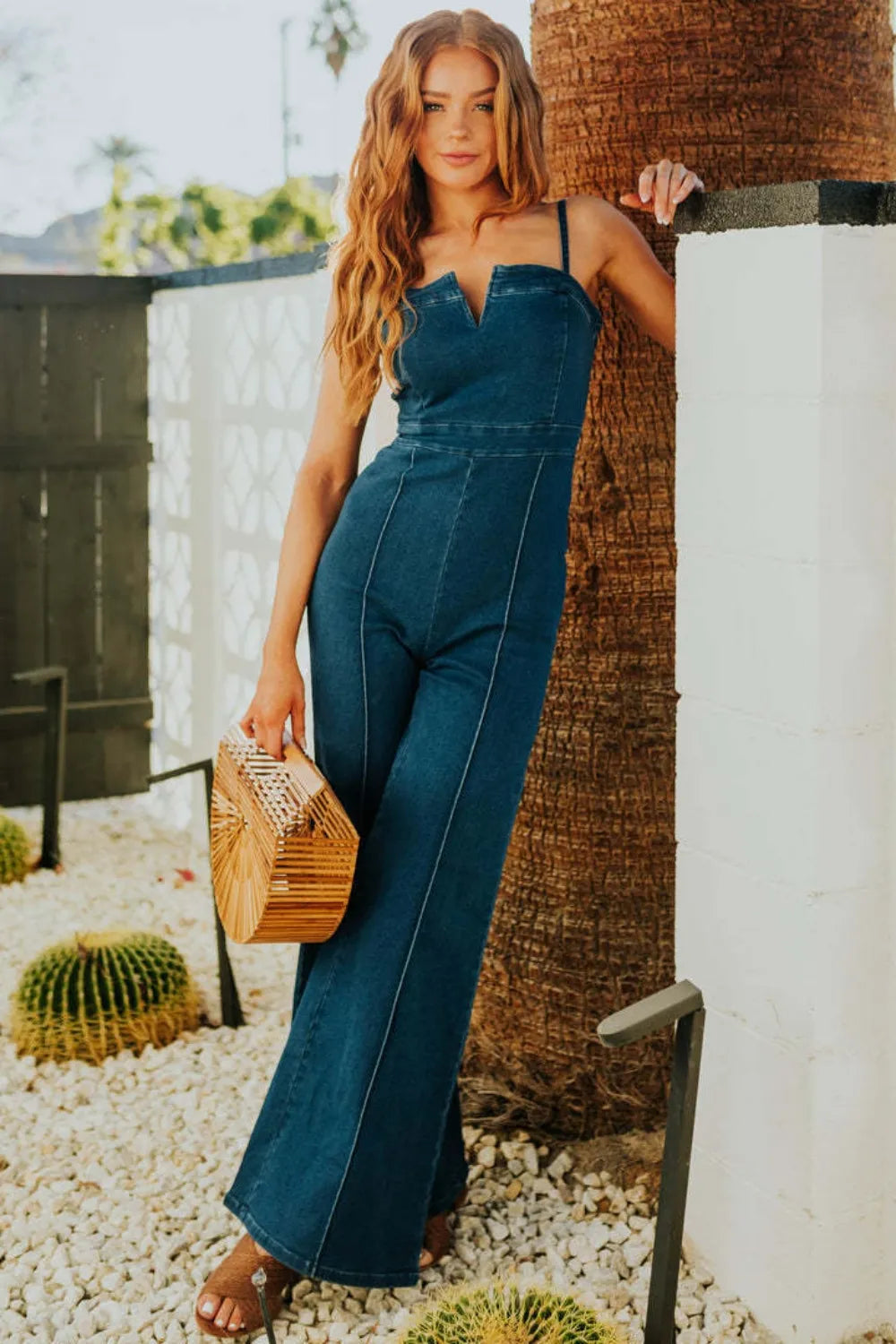 Dark blue denim wide-leg jumpsuit with spaghetti straps and fitted waist seam lines