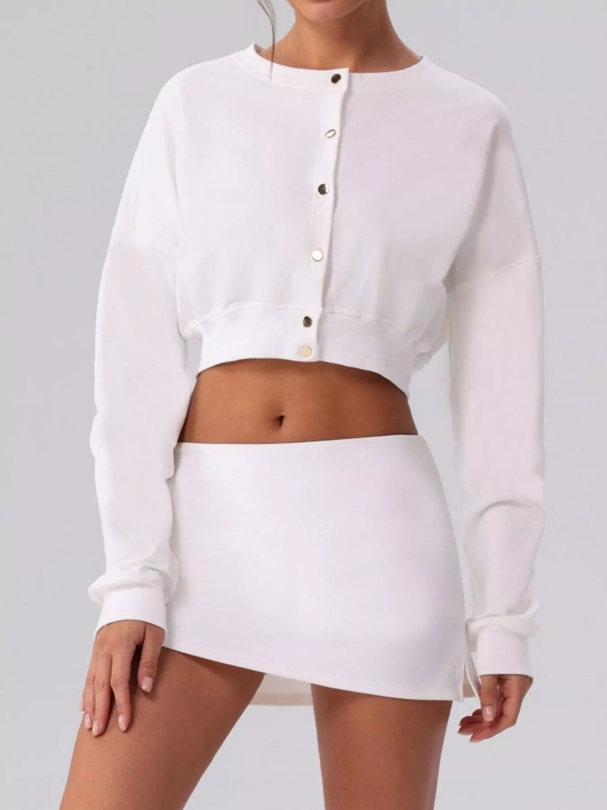 White cropped cardigan sweater with long sleeves, round neck, and button placket