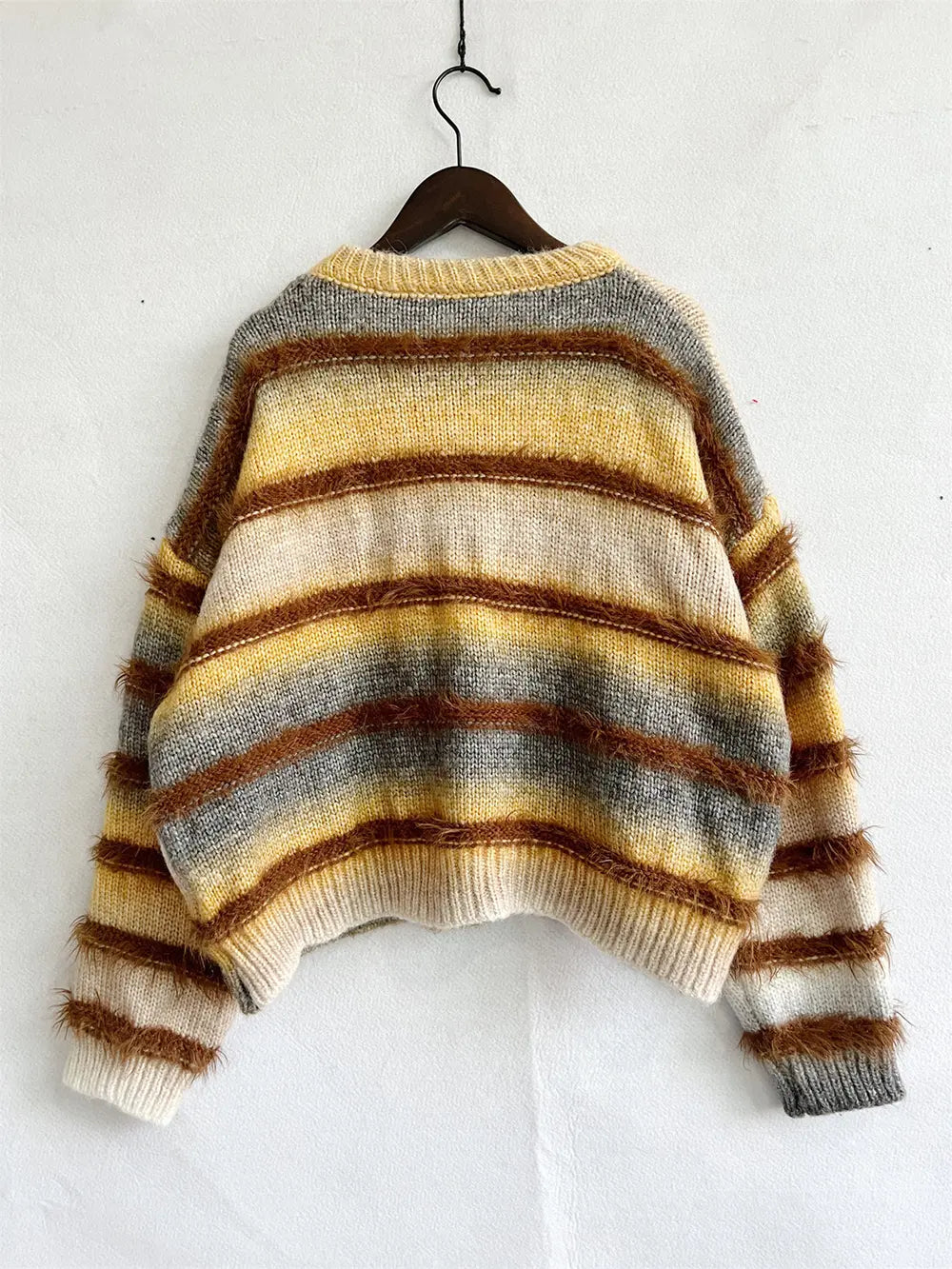 Striped round-neck long-sleeve sweater on a hanger with tan, yellow, and brown bands